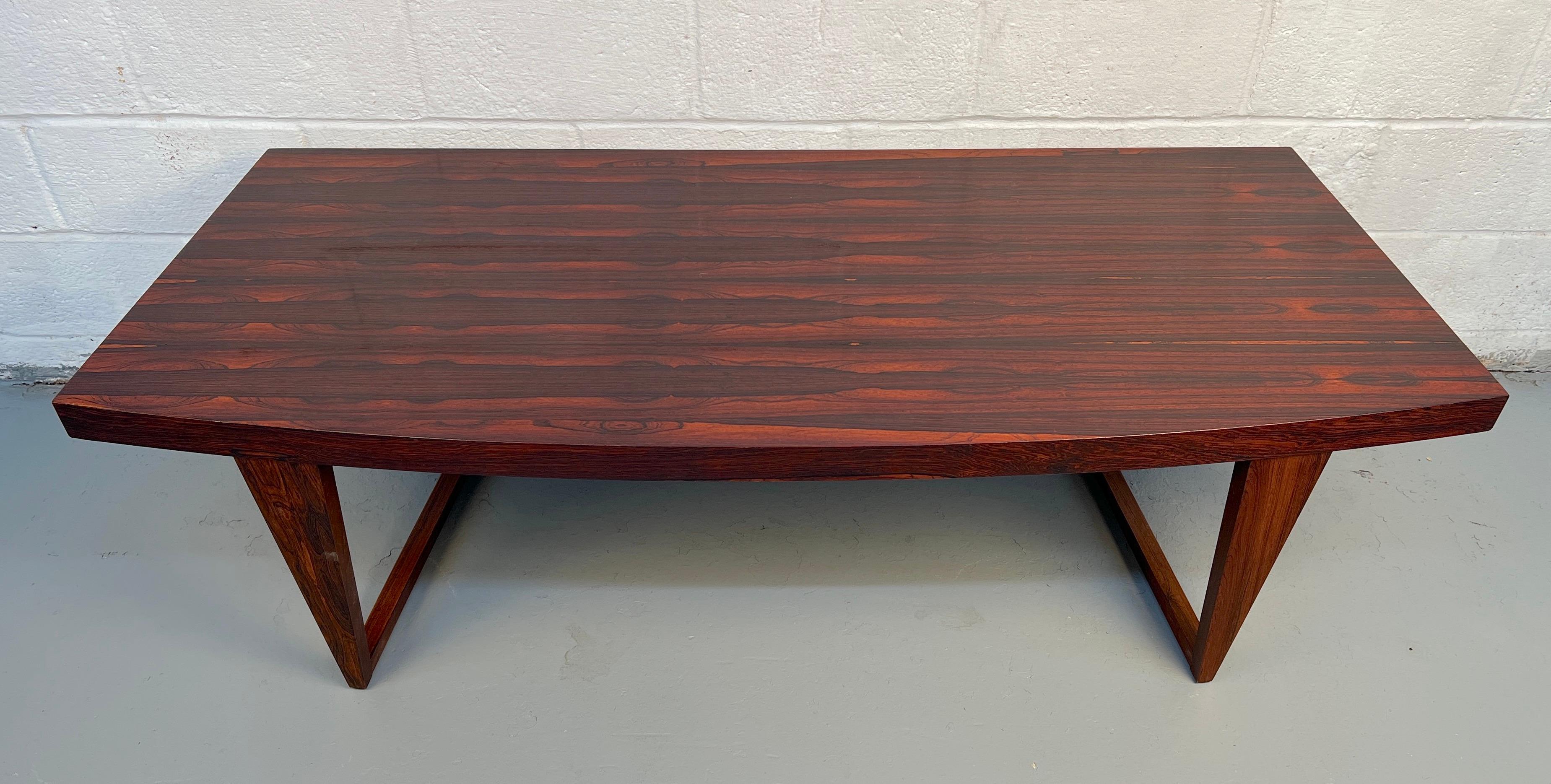 Magnifique table basse danoise moderne du milieu du siècle, fabriquée à partir d'un riche bois de rose. Le design légèrement incurvé met en valeur le grain naturel et les lignes élégantes, ce qui en fait une pièce maîtresse remarquable pour tout