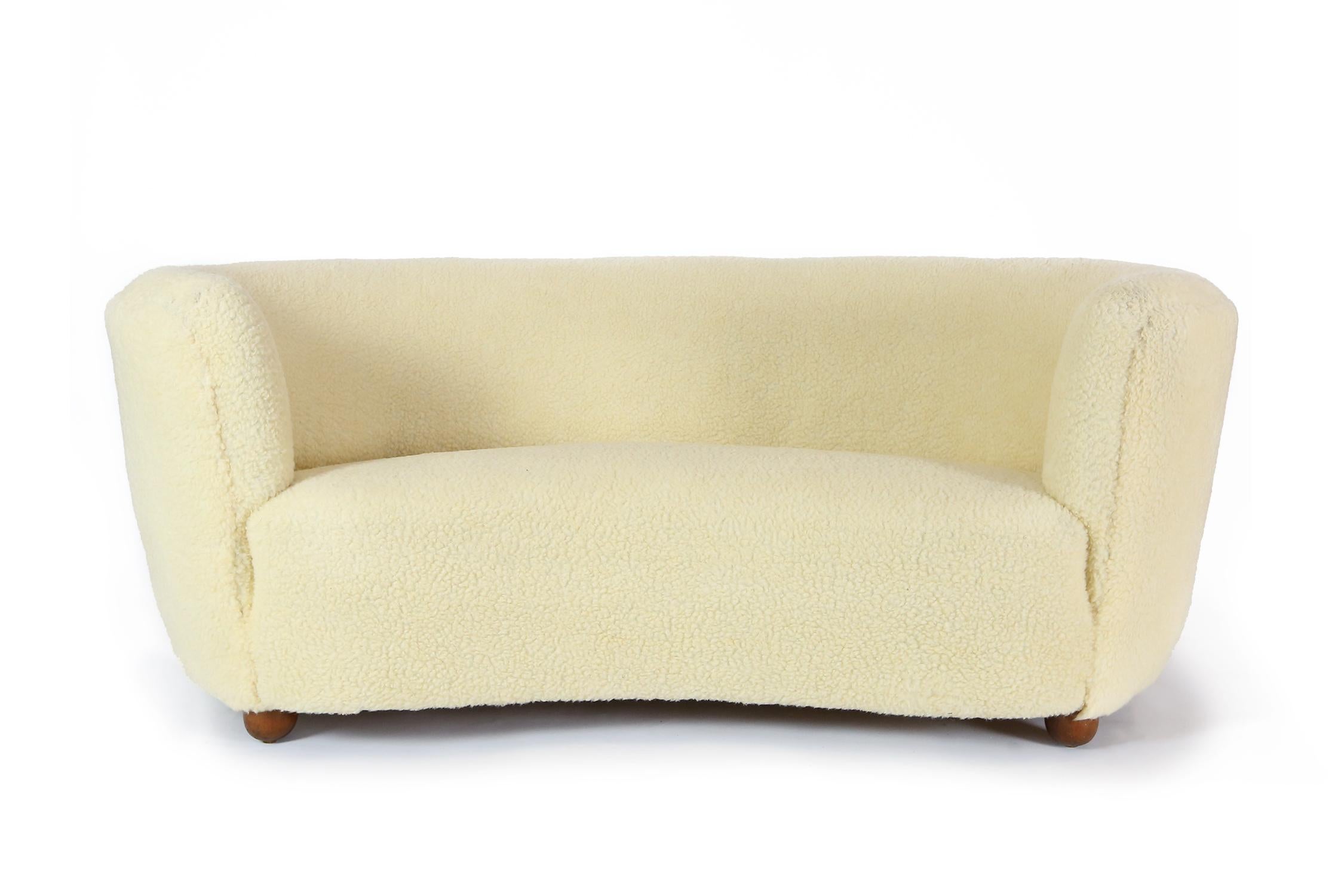 A curved Danish cabinetmakers sofa dating from the 1940s, reupholstered in sheepskin fabric.