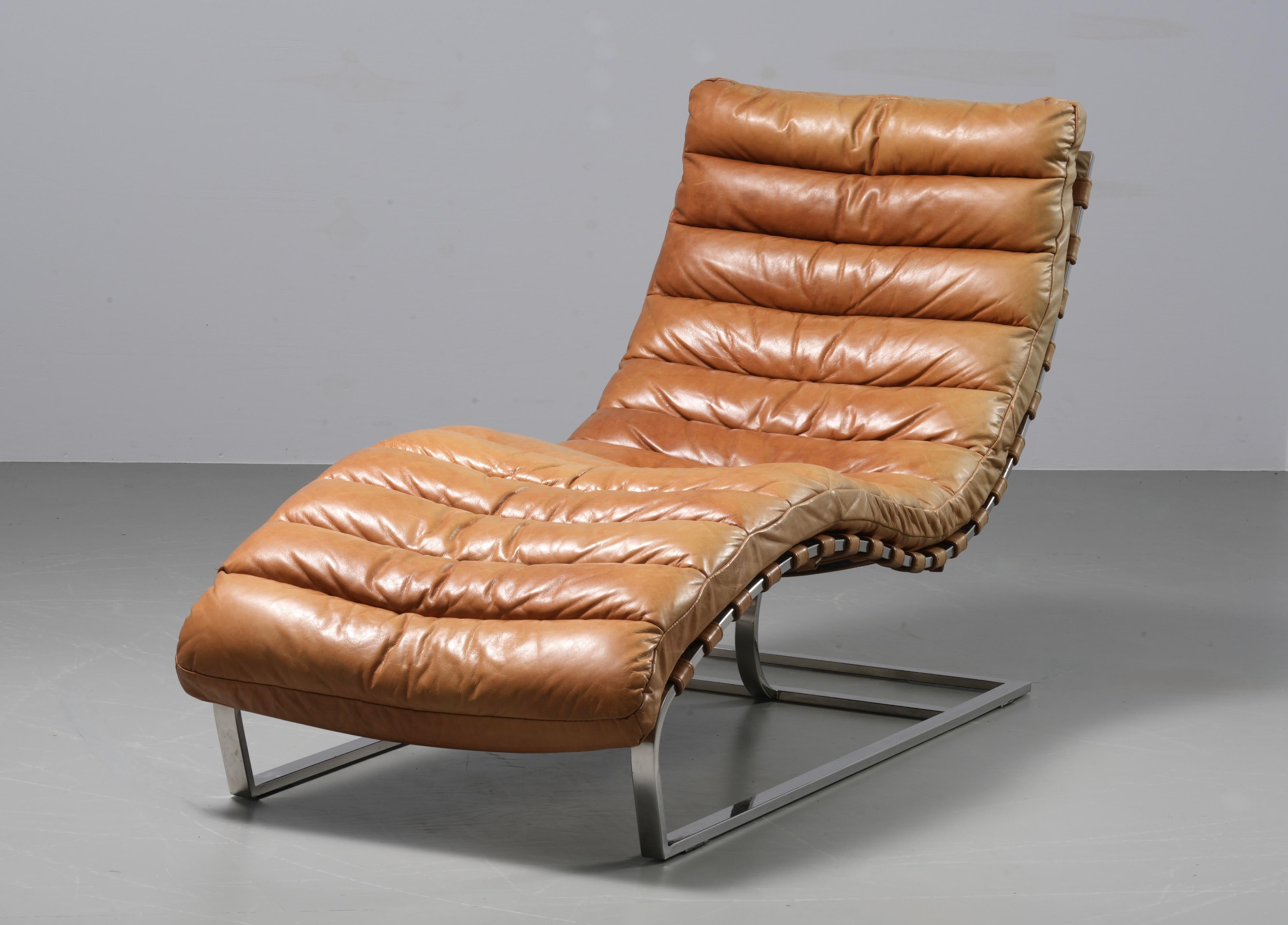 Lovely patinated cognac leather curved chaise longue. Perfect for nappies. The leather has aged very nicely and the chrome is in perfect condition. 