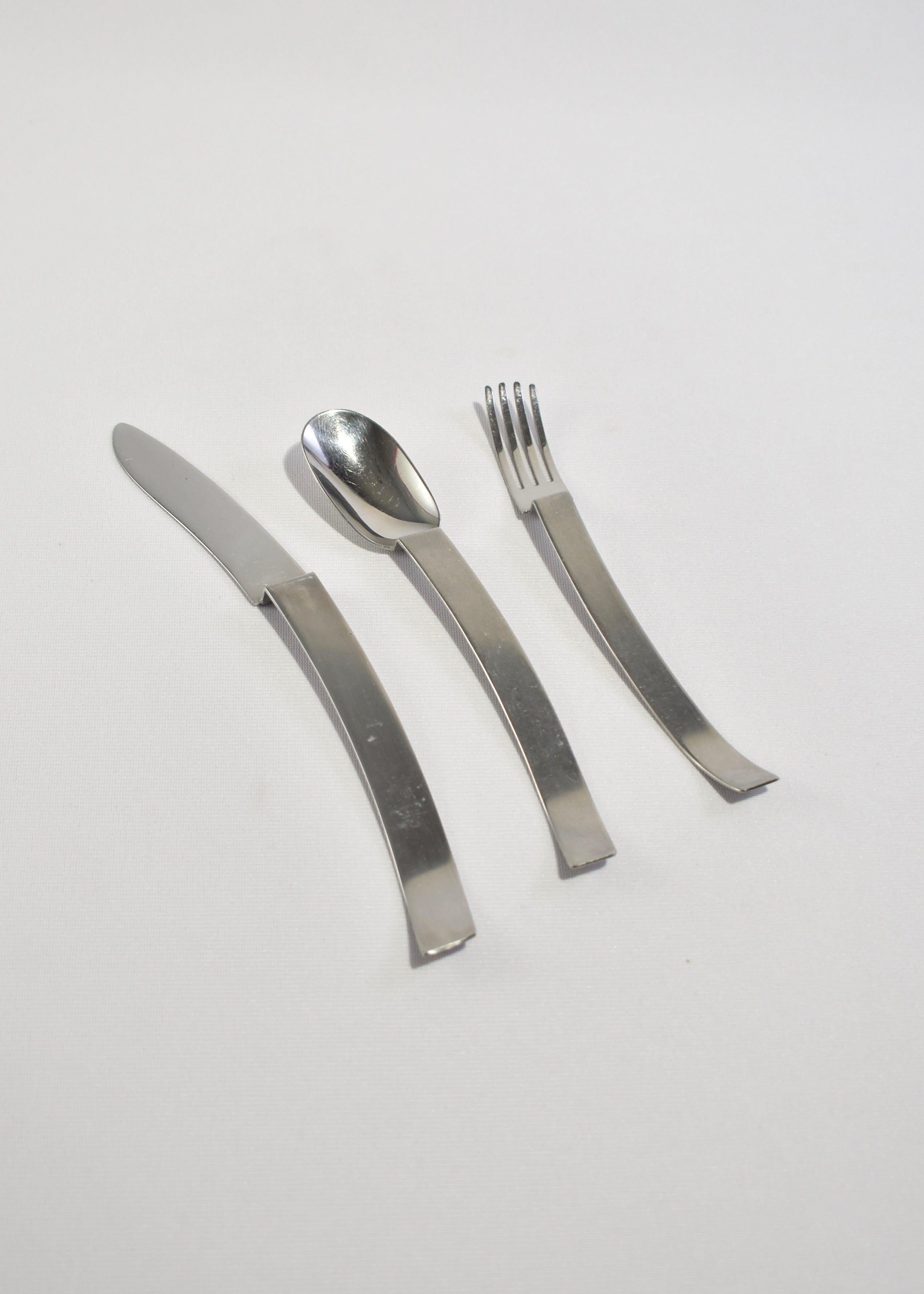 Rare, curved stainless steel flatware set of three by Kam Yamazaki. Crafted in Japan.

Purchase includes one set of three pieces.

Dimensions:
Knife: 9.5 in (24.13 cm) long
Spoon: 7.75 in (19.68 cm) long
Fork: 7.5 in (19.05 cm) long.