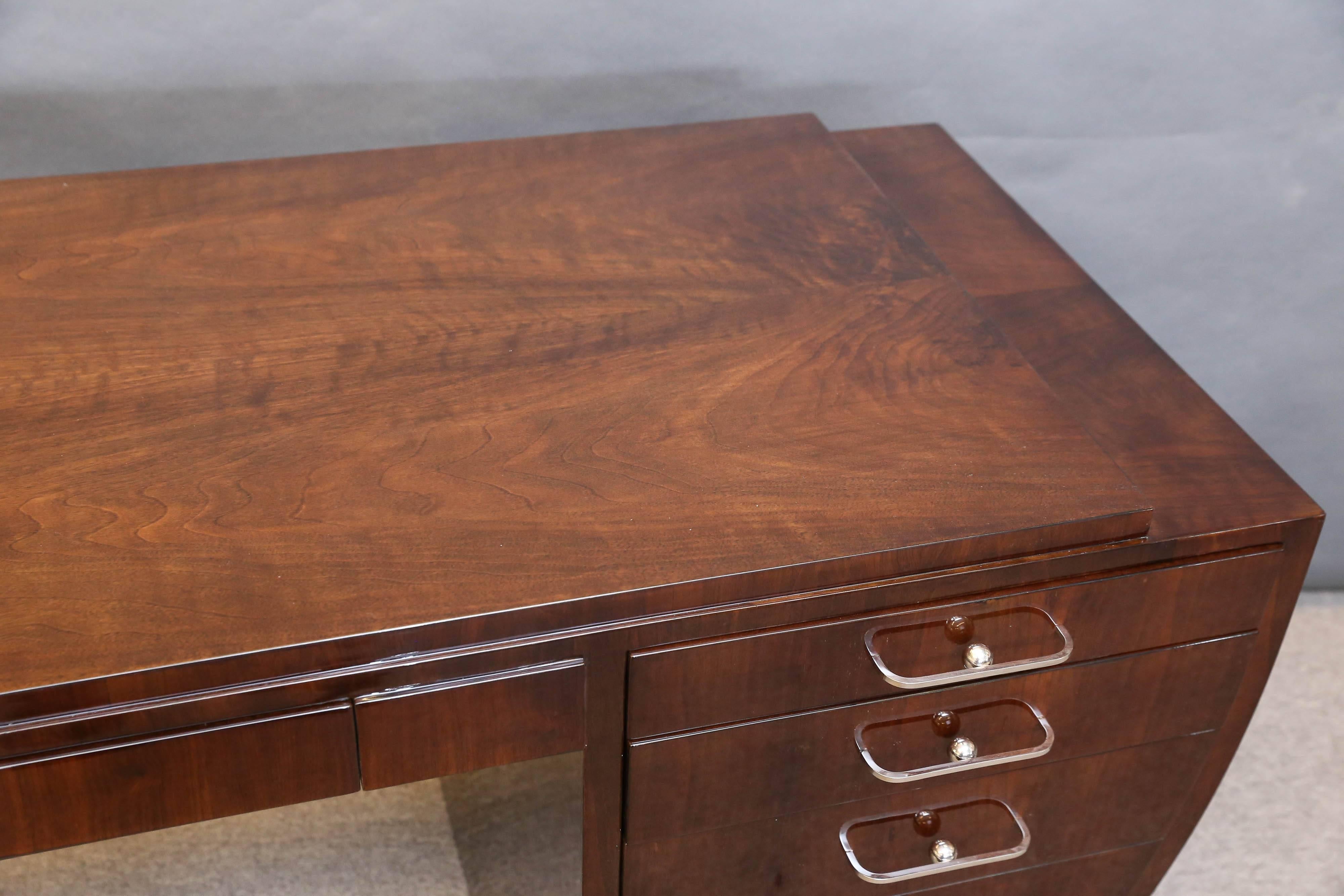 Rectangular top of the desk is elevated by the single panel on the left side and three drawers on the right side. External side on the right is curved. Each drawer has wide but thin chrome handle. Tabletop also has wide keyed drawer. 

 Condition