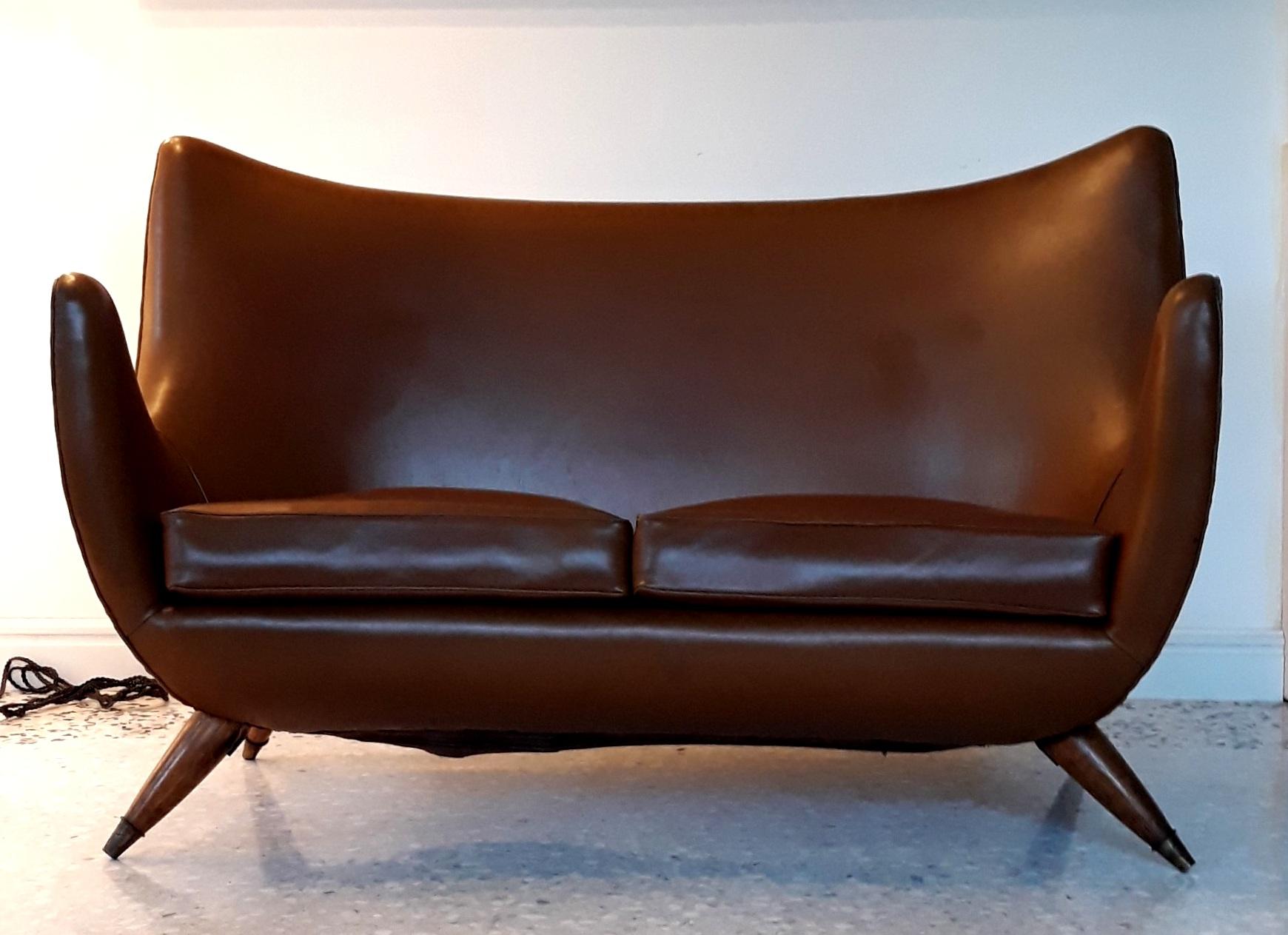 Nice two places curved sofa with very representative design of Italian fifties.
The wood legs with brass feet are prominent and strongly inclined.
The shape is intentionally curved.

The structure and the original cover are in good original