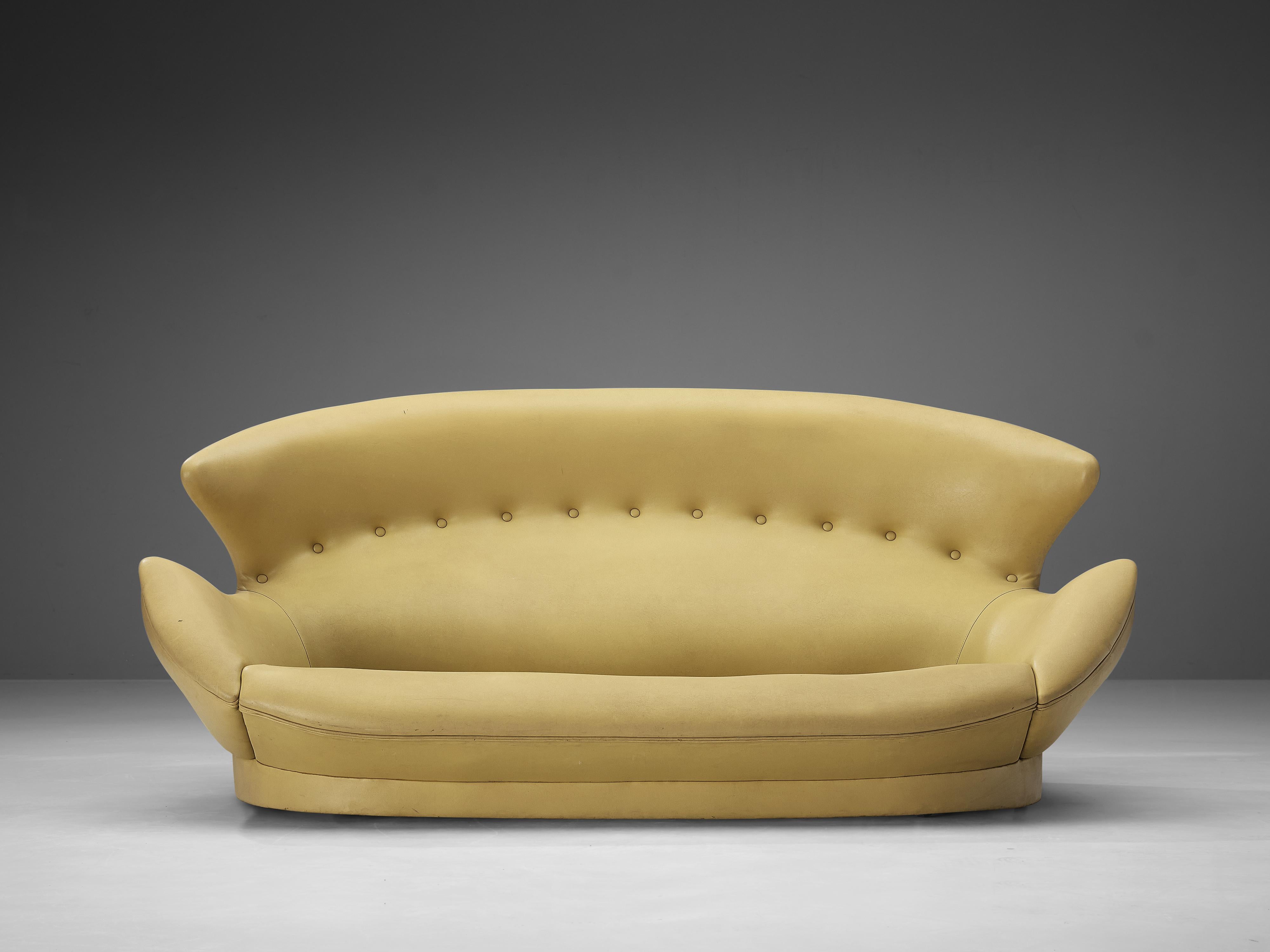 Italian sofa, leatherette, oak, Italy, 1970s

Comfortable winged sofa in yellow faux-leather upholstery. The rounded overall shape of the piece, with the wings reaching towards the armrests, makes sure that the sofa almost hugs the seaters. 