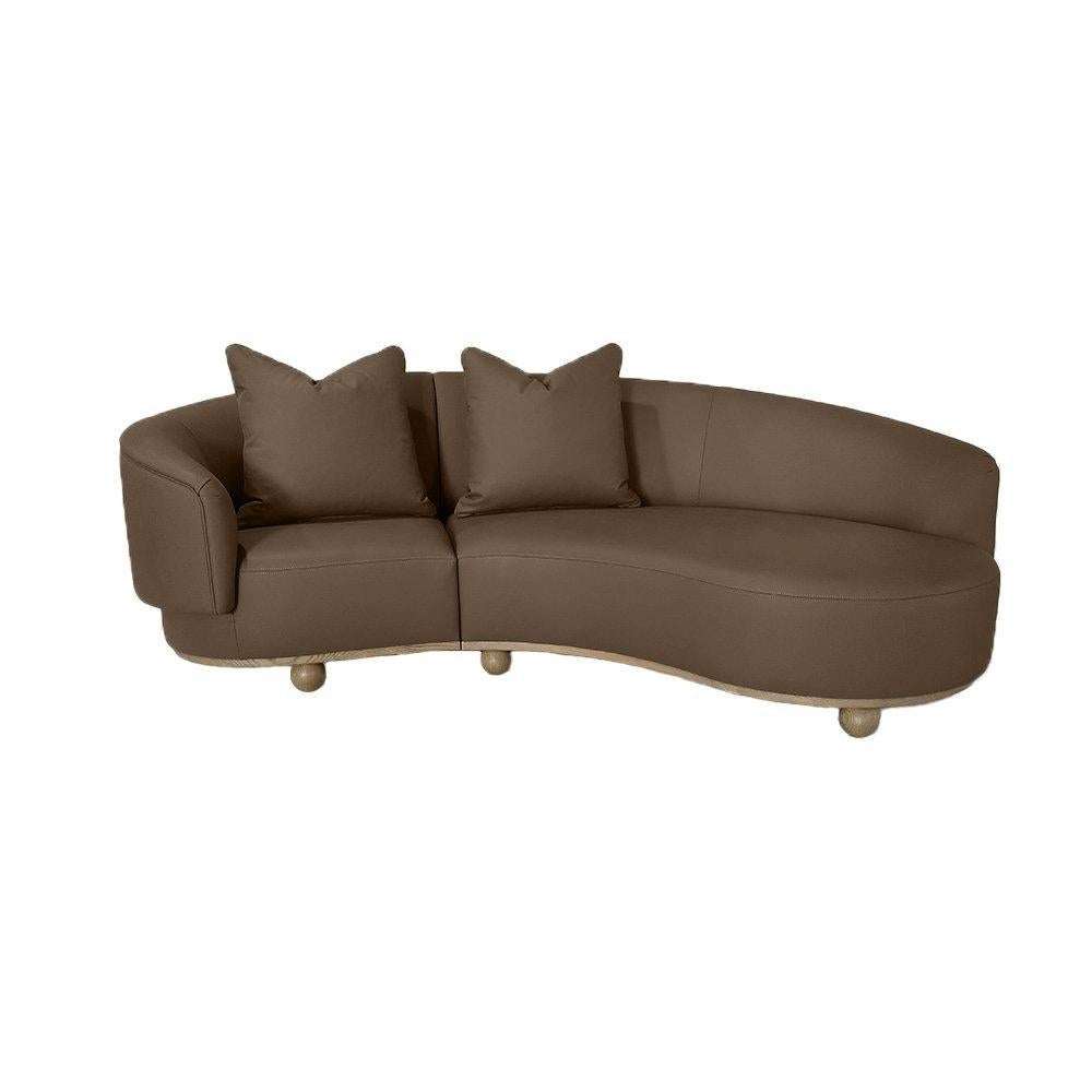 Das geschwungene Sofa ist ein modernes und minimalistisches Möbelstück mit einem schlanken Design, das sich durch klare Linien auszeichnet. Er verfügt über eine geschwungene Struktur, die aus hochwertiger massiver Eiche und echtem Leder gefertigt