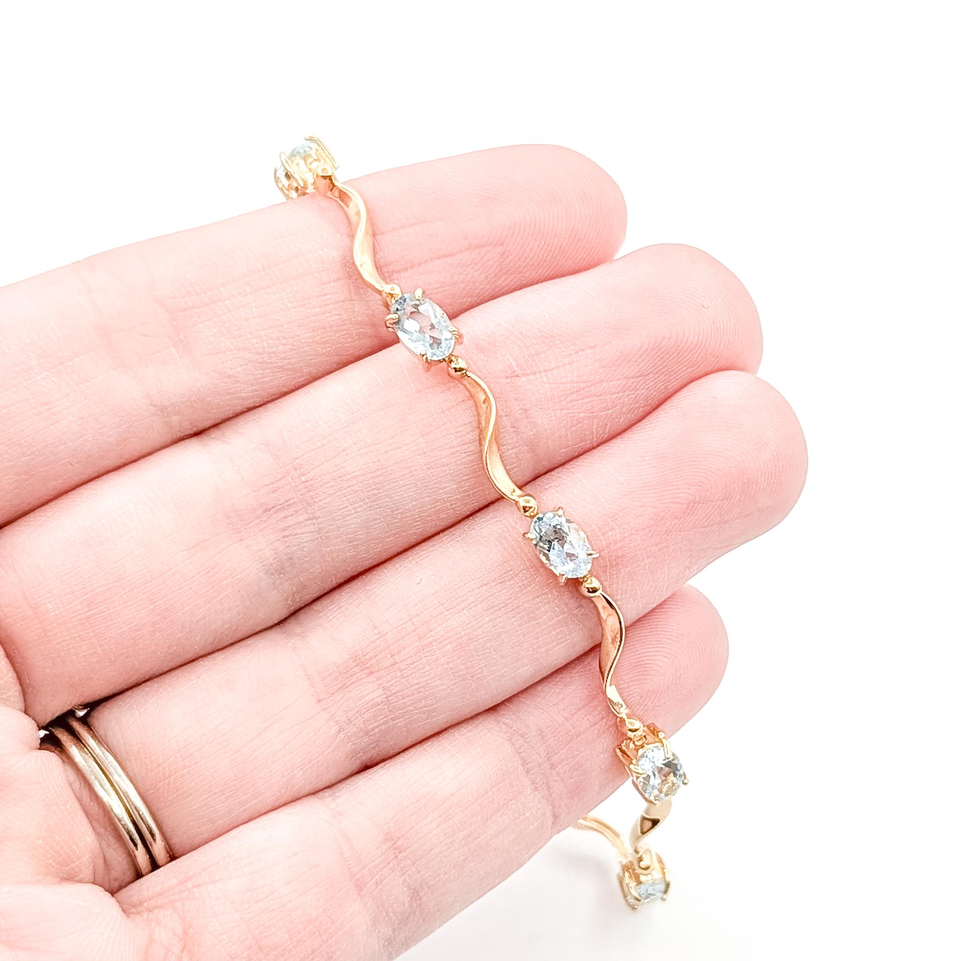 Questo delizioso bracciale è realizzato in oro giallo 14k e presenta serene acquemarine blu cielo, ciascuna saldamente incastonata lungo una maglia delicatamente curva. Il motivo a onde morbide tra ogni gemma conferisce al bracciale un aspetto