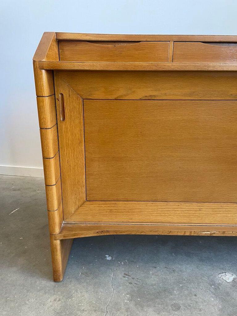 Curved oak server by Harold Schwartz for Romweber by, marked on drawer interior with a satin label. This stunning piece has four green felt lined drawers above two sliding door cabinets with shelving, storage, and additional drawers. Back of piece