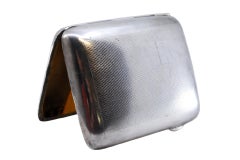 Curved, perforated silver cigarette case with a gold interior and a hinged lid