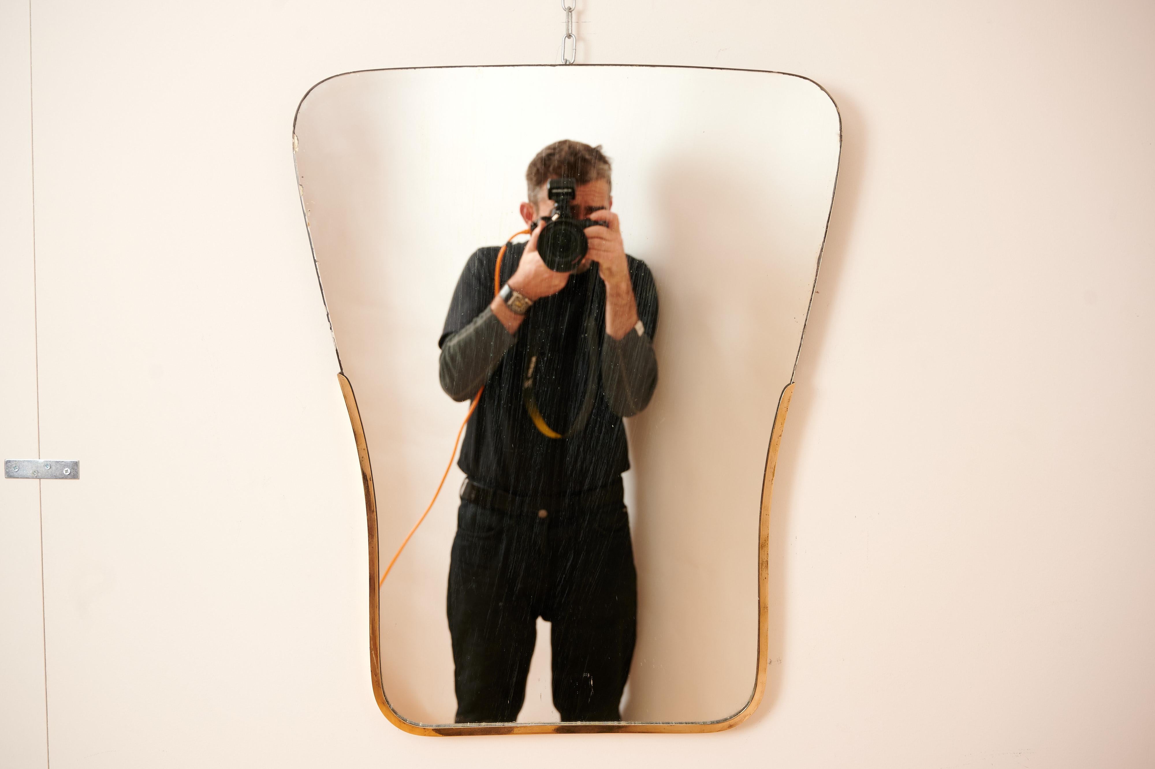 An unusual Gio Ponti style mirror with a brass frame to the lower half of the mirror.

