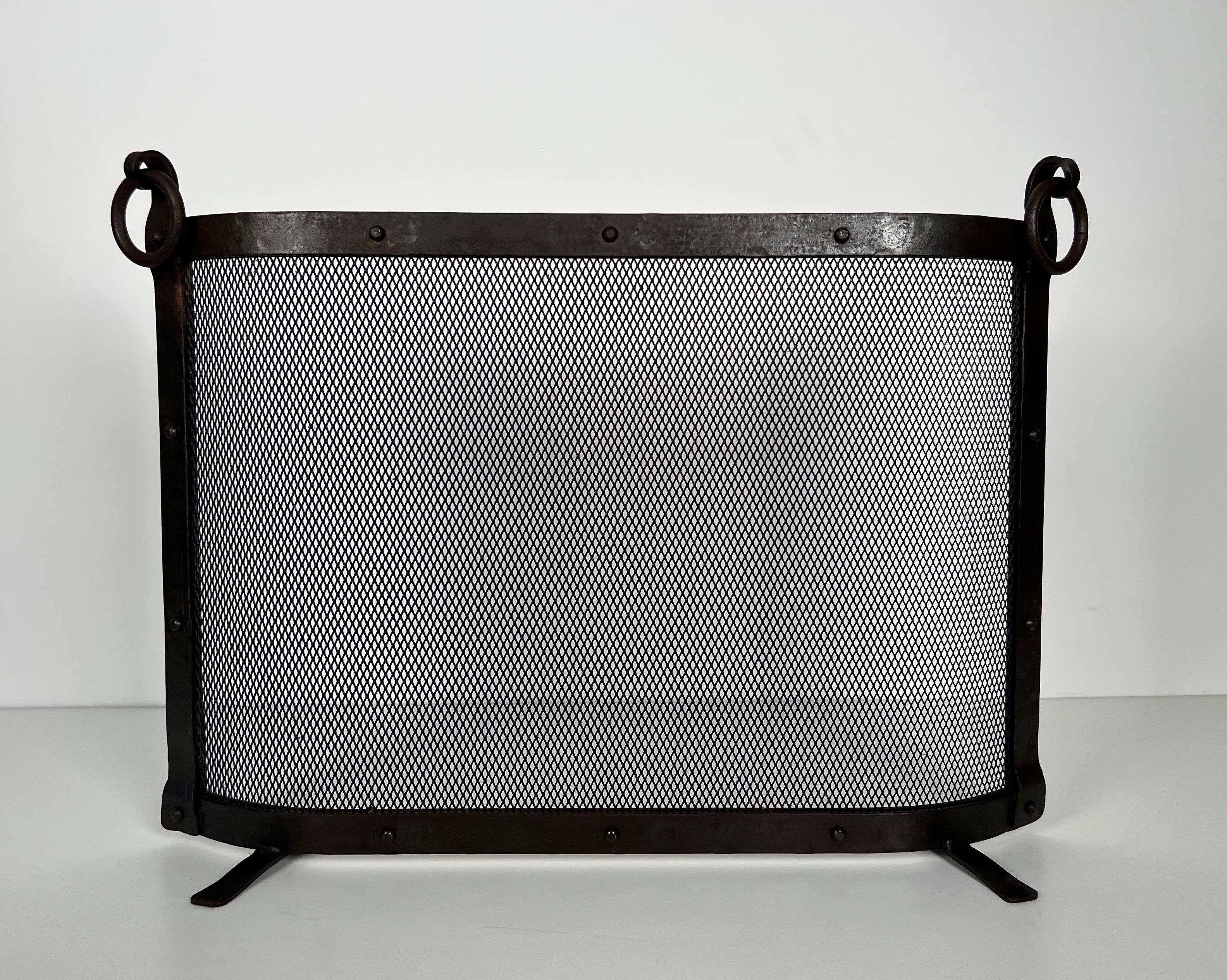 This nice curved fireplace screen is made of a steel grilling surrounded by a thick riveted wrought iron frame with rings. This is a French modernist work in the style of Jacques Adnet. Circa 1940