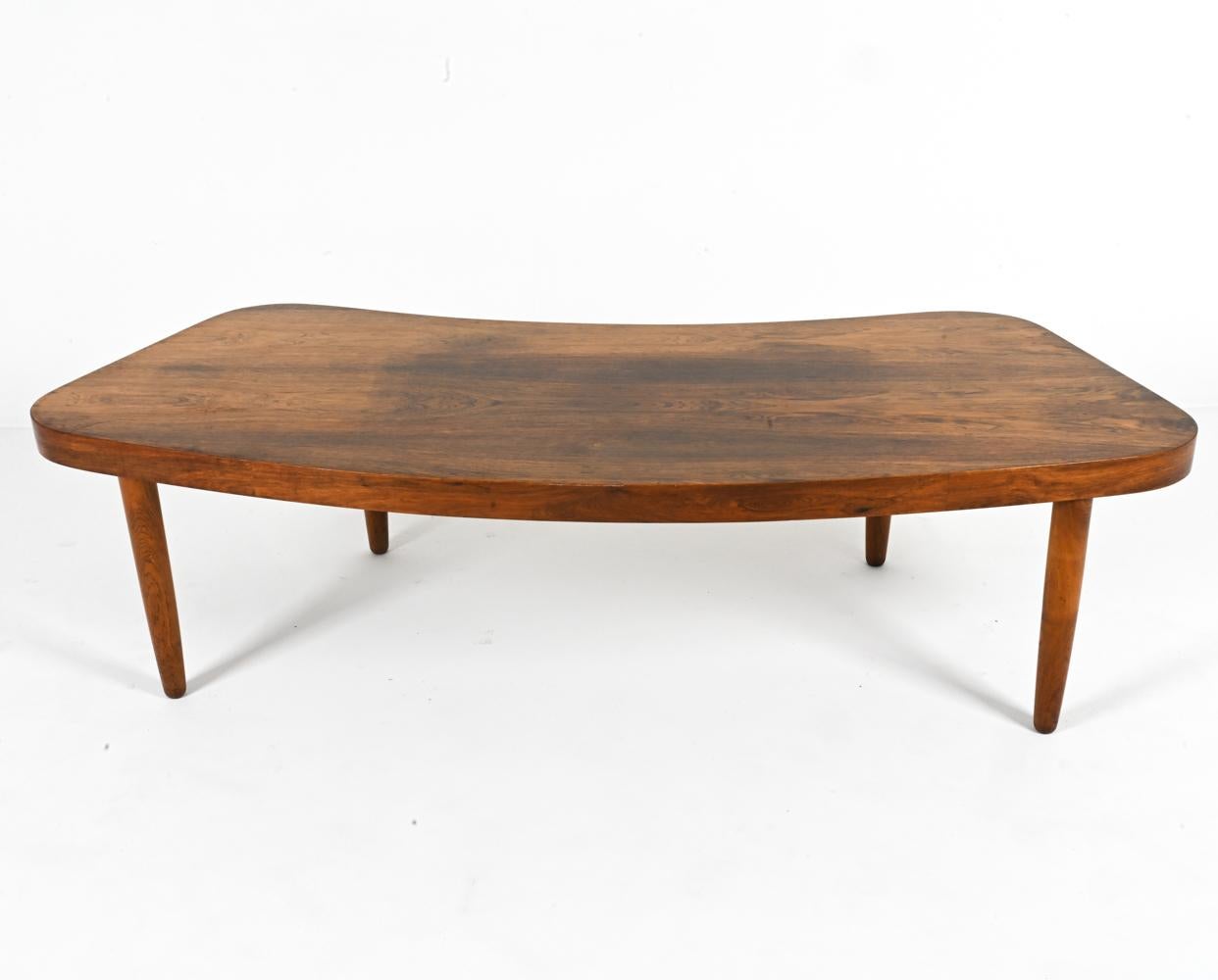 This captivating Danish coffee table, crafted from rich rosewood in the 1960s, embraces the elegance and intrigue of organic forms, combined with  functional design. Its distinctive curved silhouette adds a touch of sculptural beauty to any space,