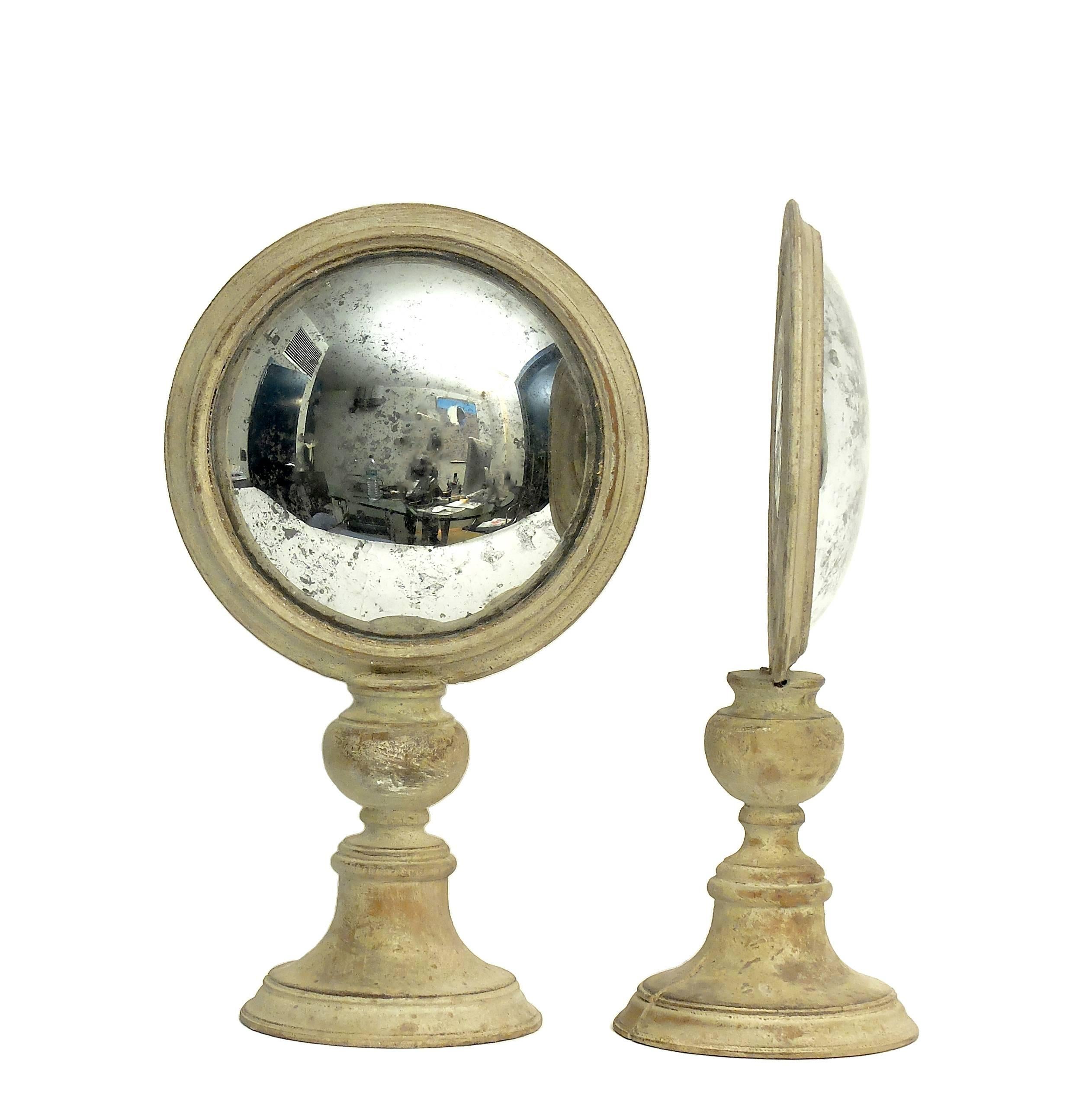A couple of Wunderkammer round curved mirrors with white wooden frames mounted over white wooden round bases on the rear of the frame there is one round malachite stone.