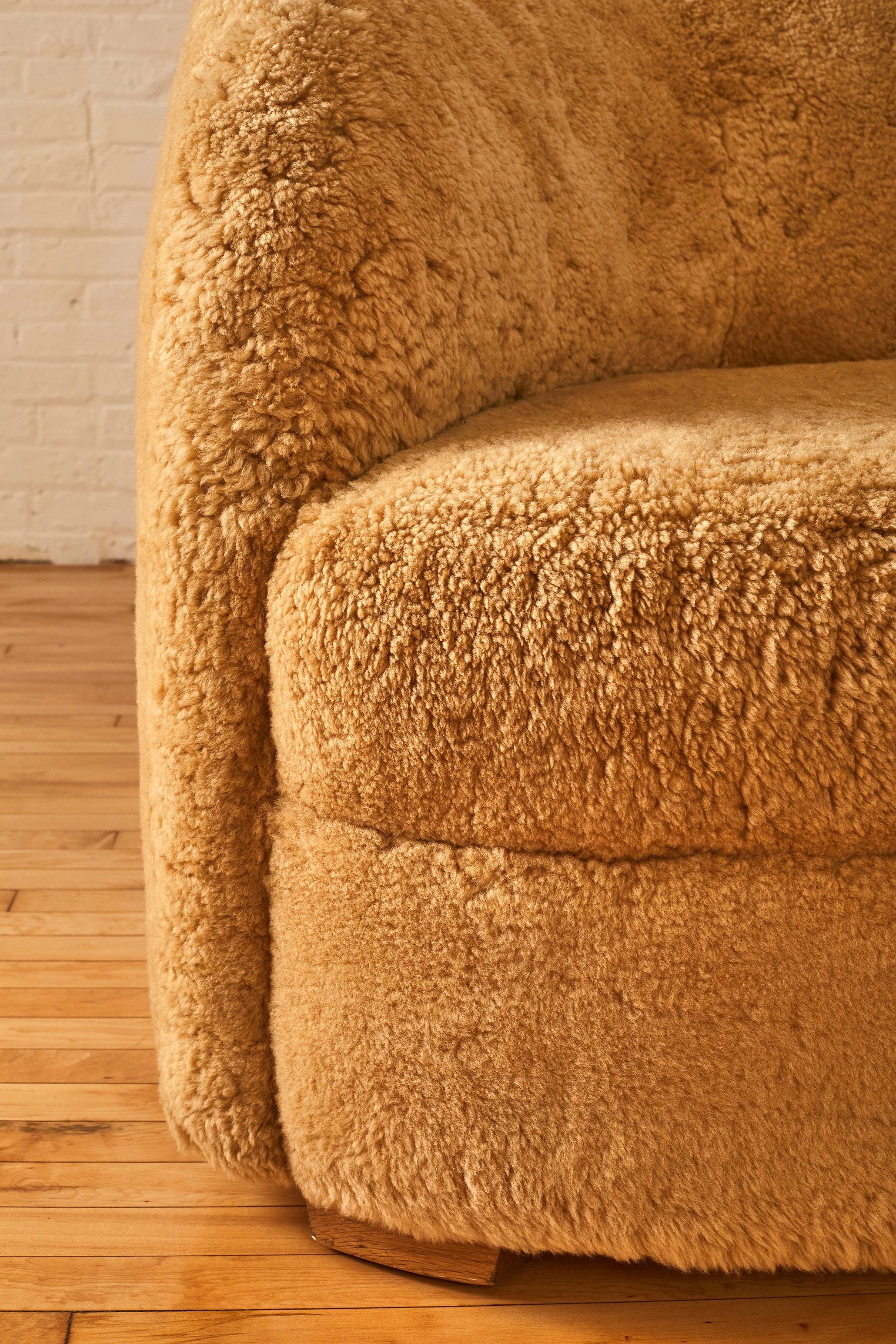 Mid-Century Modern curved sofa in shearling upholstery on pine legs. 

 