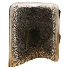 Curved silver case with engraved wreaths around monogram and gold interior