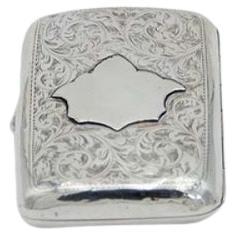 Curved silver case with engravings around monogram card