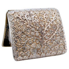 Curved silver cigarette case with flower and branch reliefs