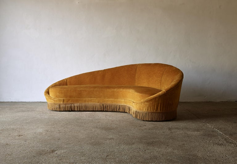 An original and authentic Italian 1950s curved comma sofa, designed by either Ico Parisi or Federico Munari. The sofa retains its original fabric and tassles and is of curved organic form with its original sprung cushion and conical beech feet.