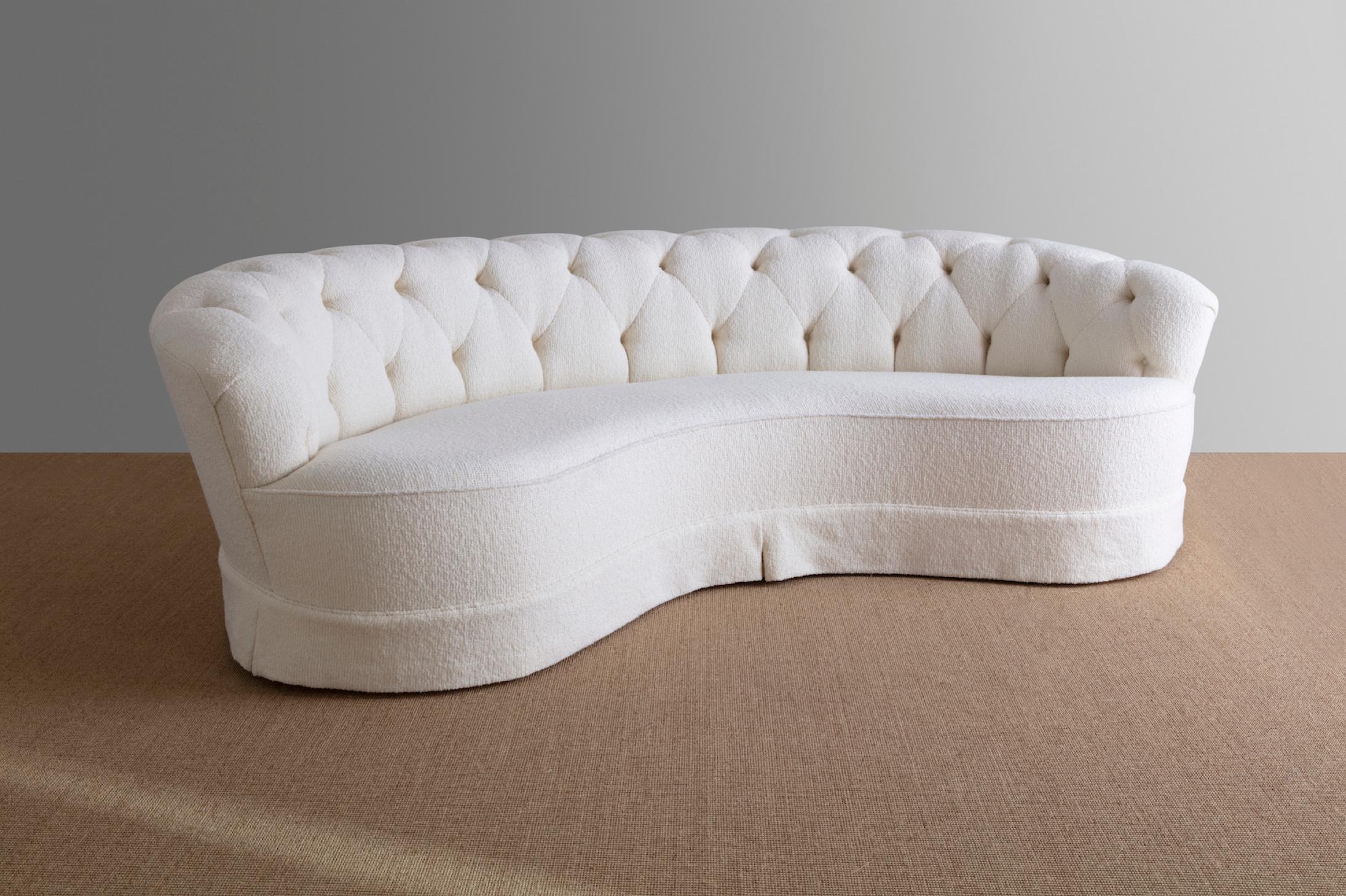 Curved sofa in ivory bouclé upholstery with button tufted backrest. Designed by Greta Magnusson Grossman for Barker Brothers, Los Angeles, 1941-42. Upholstered with 