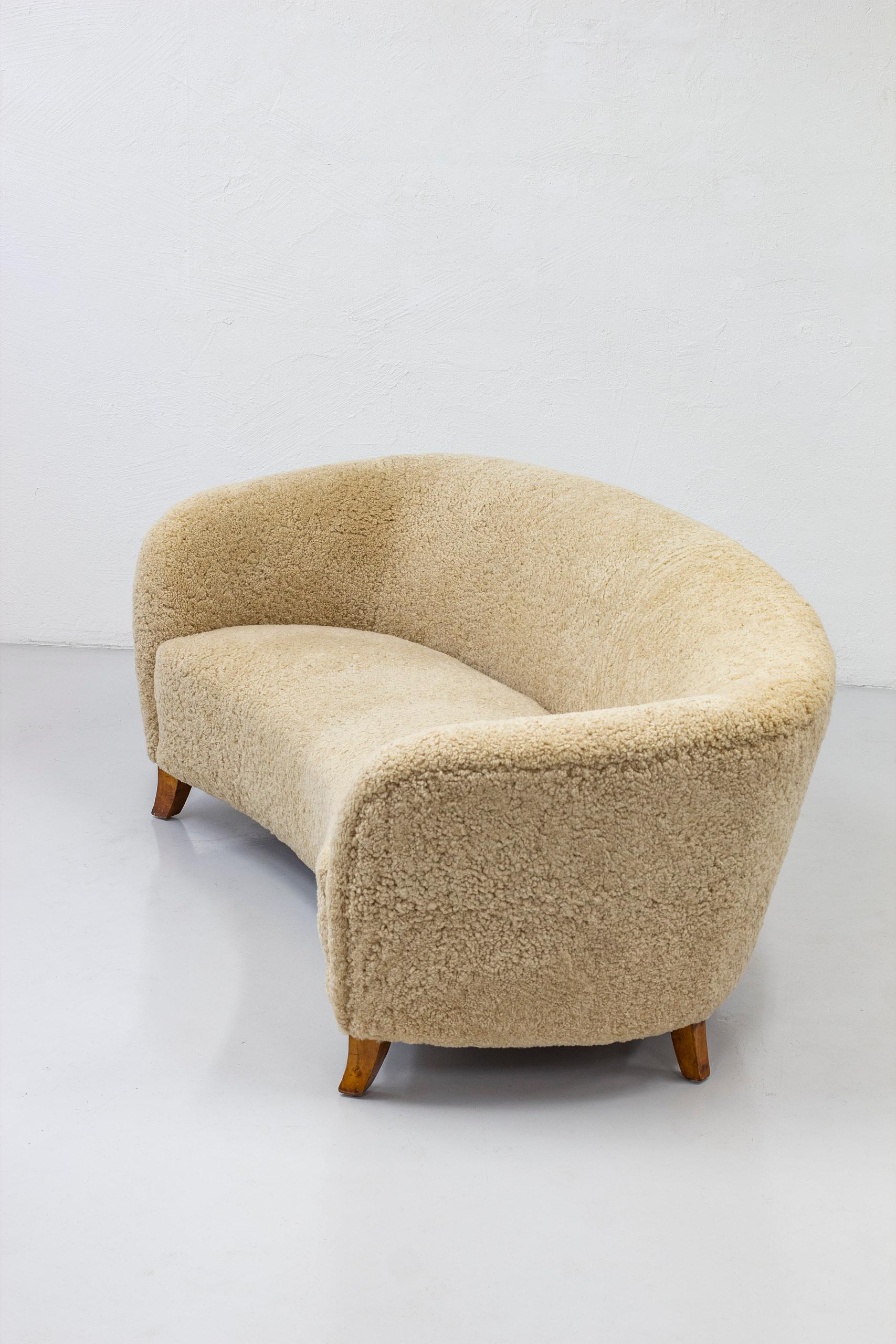 Curved Swedish modern sofa designed and made in Sweden during the 1930-40s. Curved birch legs and new sheep skin upholstery in light beige color. Seating three persons. Great comfort and design. New upholstery without remarks. Legs with light age