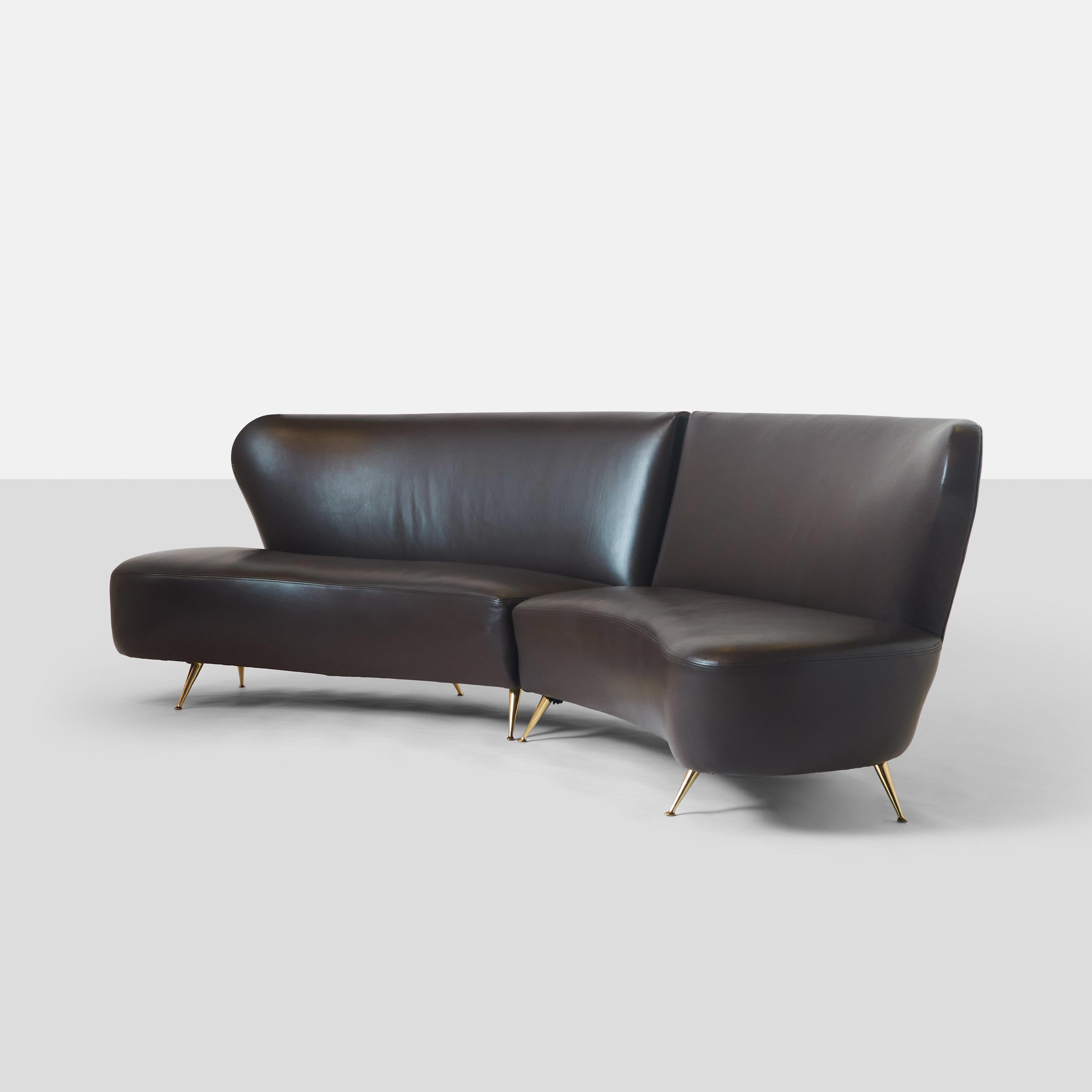 A leather two piece sectional sofa by Carlo di Carli. When placed side by side, the pieces create a gently curved symmetrical sofa. Each section has 5 brass feet, 2 at front and 3 at back.