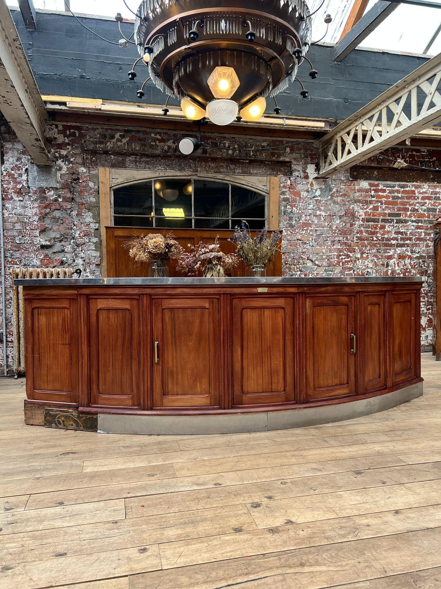 Elegante bar in legno curvato con una splendida facciata a pannelli in legno dai toni caldi e un piano e uno zoccolo in acciaio inox. L'artigianato mostra la qualità tipica dei mobili da bar francesi dell'inizio del XX secolo, progettati sia per