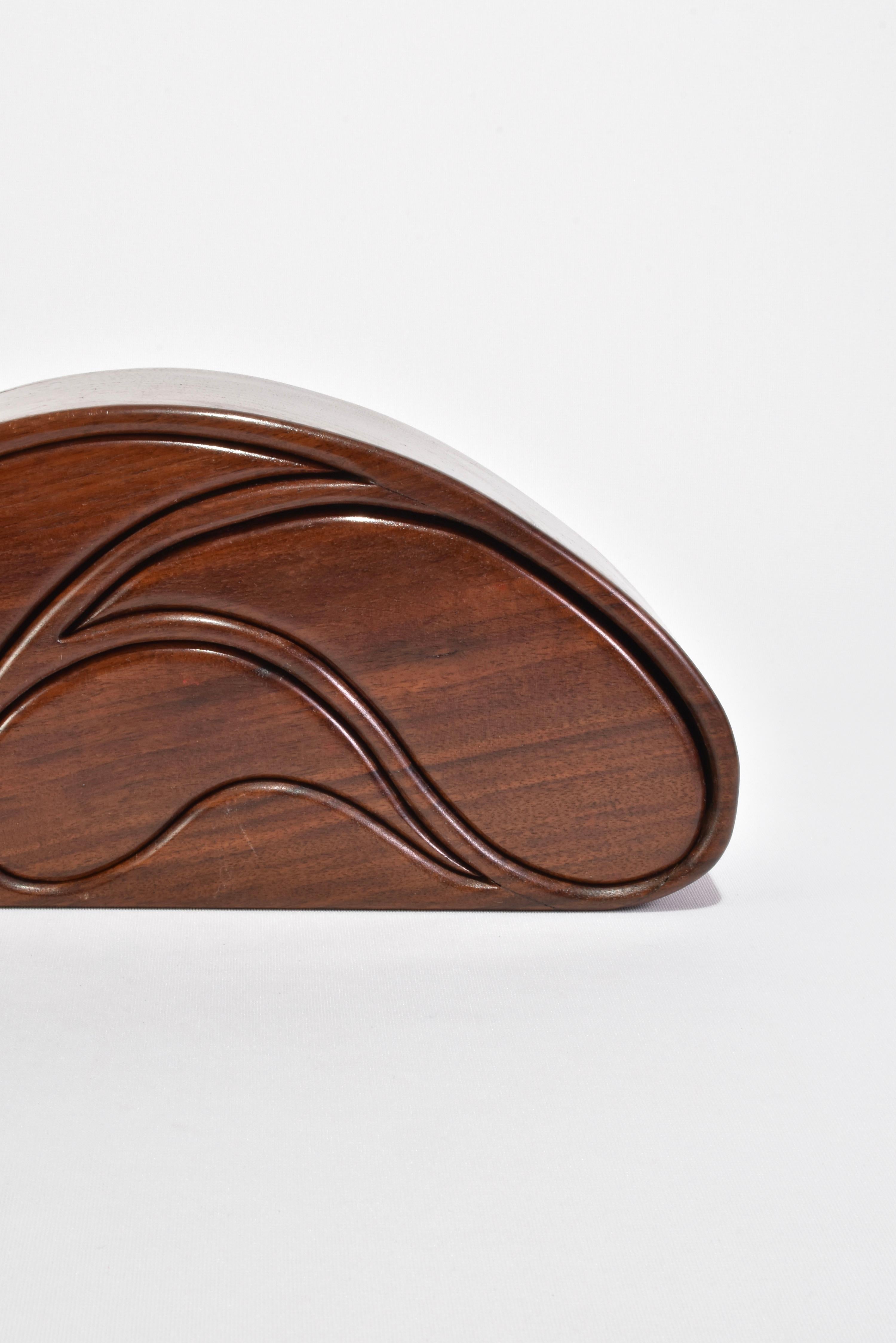 Hand-carved wooden jewelry box in a curved shape with three drawers and five compartments lined in red felt.