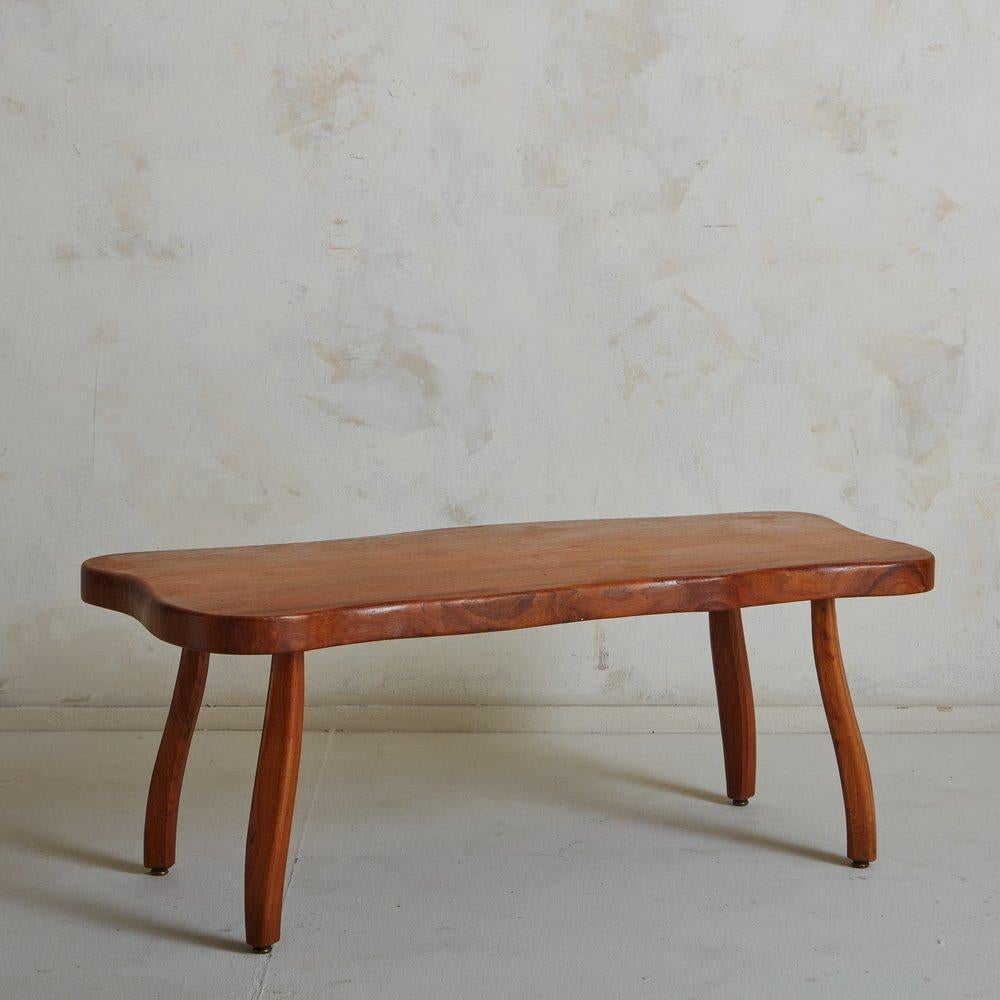A Mid Century French wooden coffee table featuring beautiful wood graining. This table has curvilinear edges and stands on four subtly curved legs with circular metal feet. Sourced in France, 1960s.

