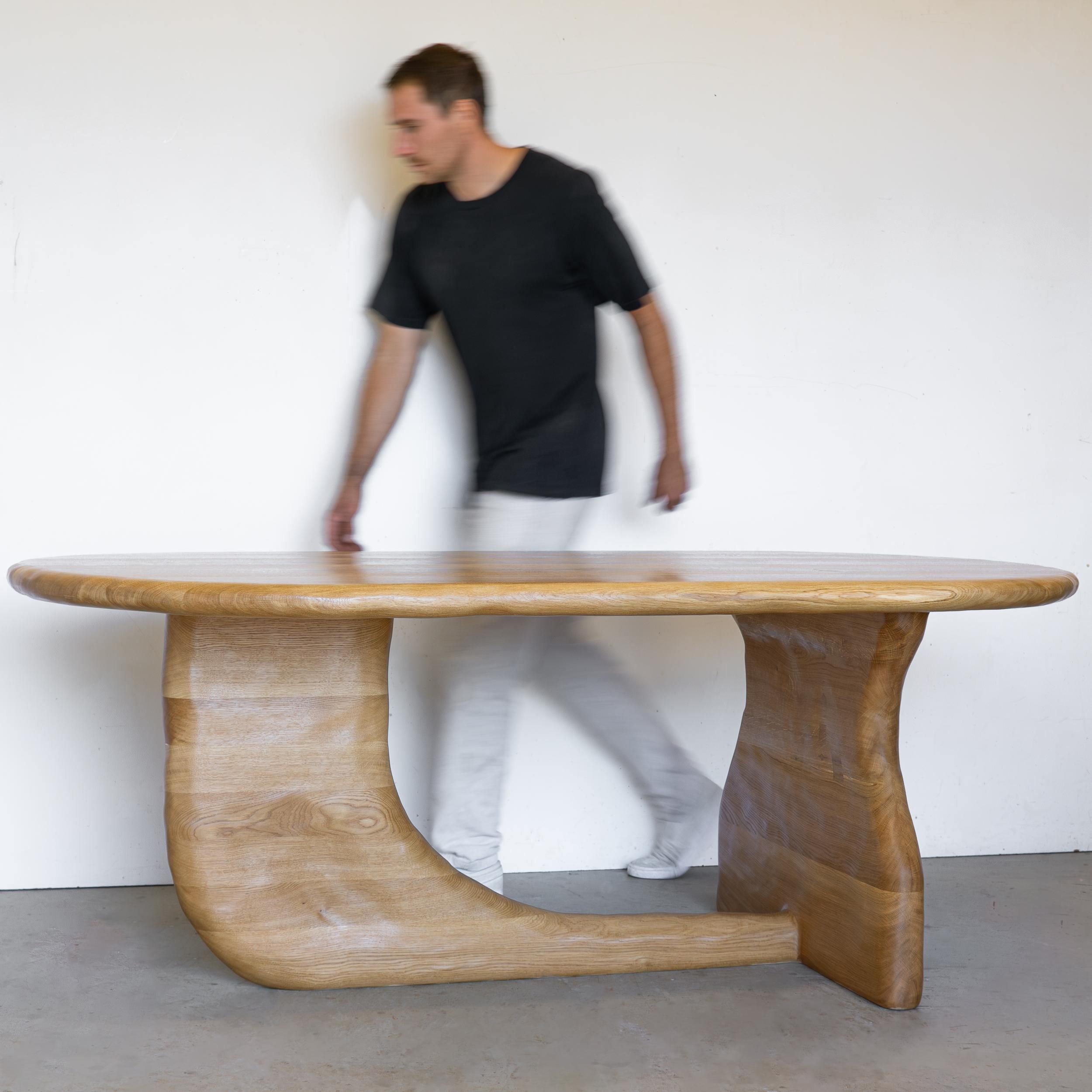 The Curvo Dining Table is sculpted using various hand tools, making each piece unique with its own distinctive wood grain. The sculptural table is characterized by its seamless flow, with no sharp edges or corners. It is crafted from a one piece of