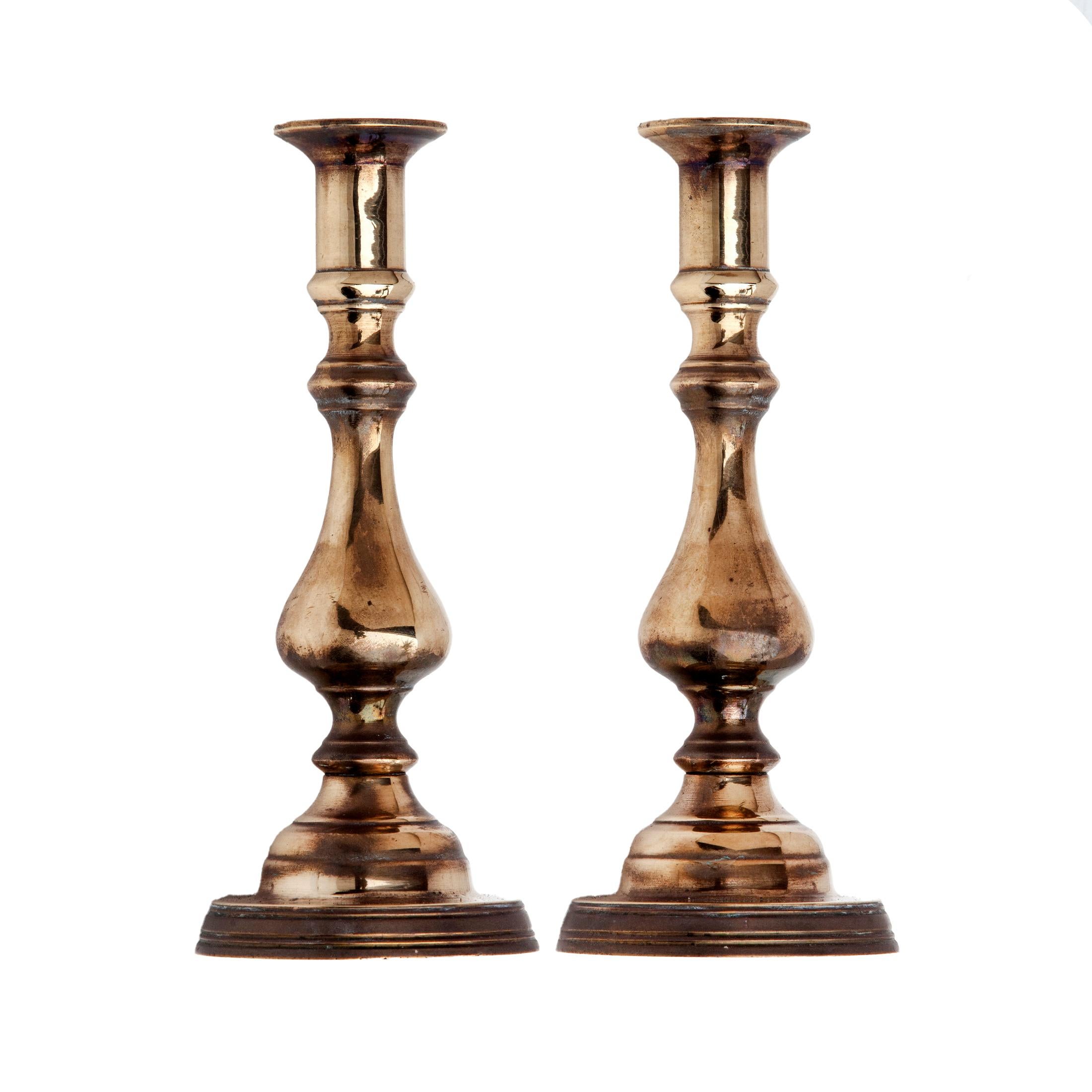Candelieri in ottone massiccio con design a balaustro.   
Aggiungi eleganza al tuo tavolo o al tuo caminetto con questa coppia di candelieri in ottone di qualità. I gambi a balaustro si ergono da basi rotonde. 
Sono in eccellenti condizioni vintage