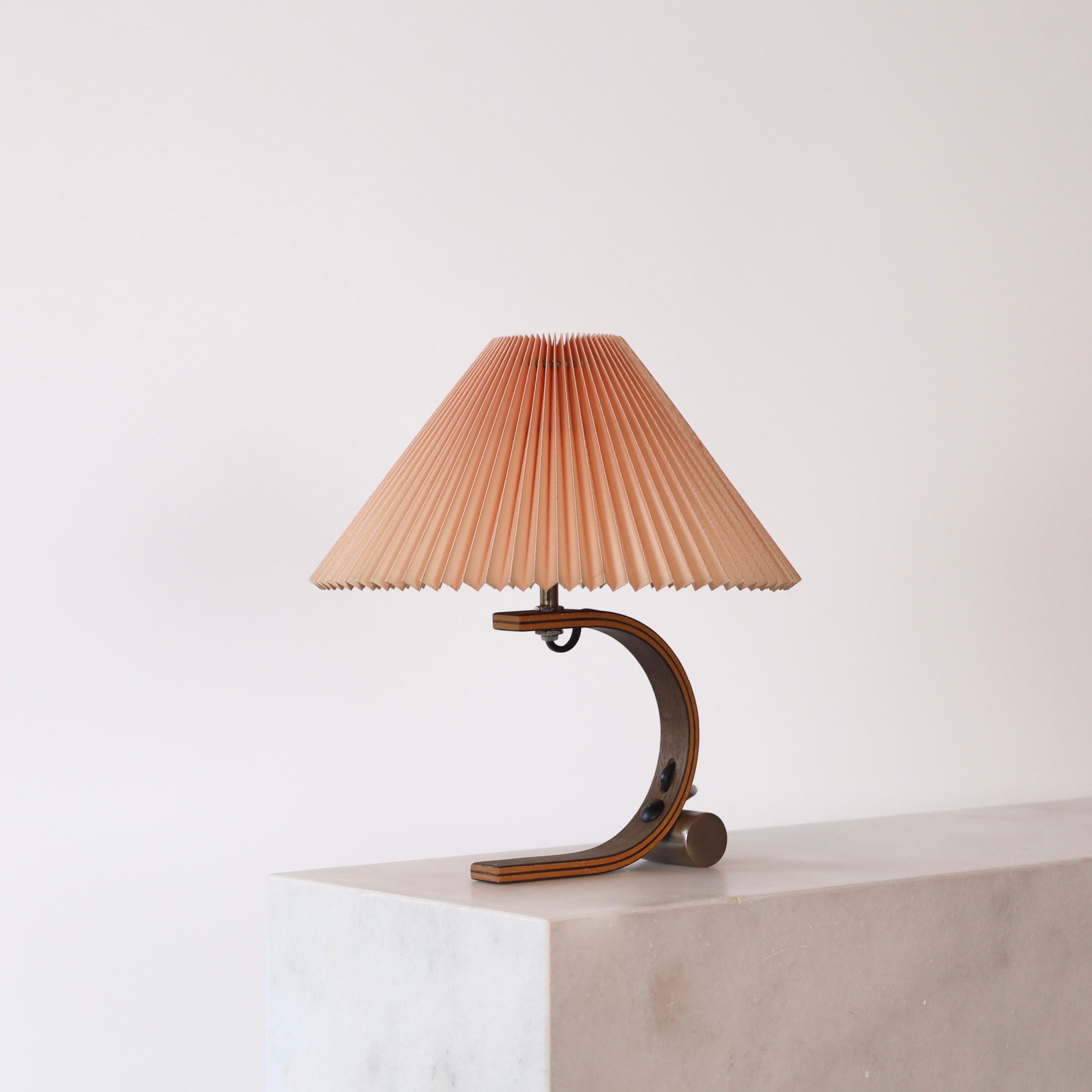 A table lamp in smoked oak wood designed by Mads Caprani in the 1970s for Caprani Light. All original. A rare find for a beautiful home.

* A bend oak wood veneer table lamp with and a pleated clip-on fabric shade
* Designer: Mads Caprani
*