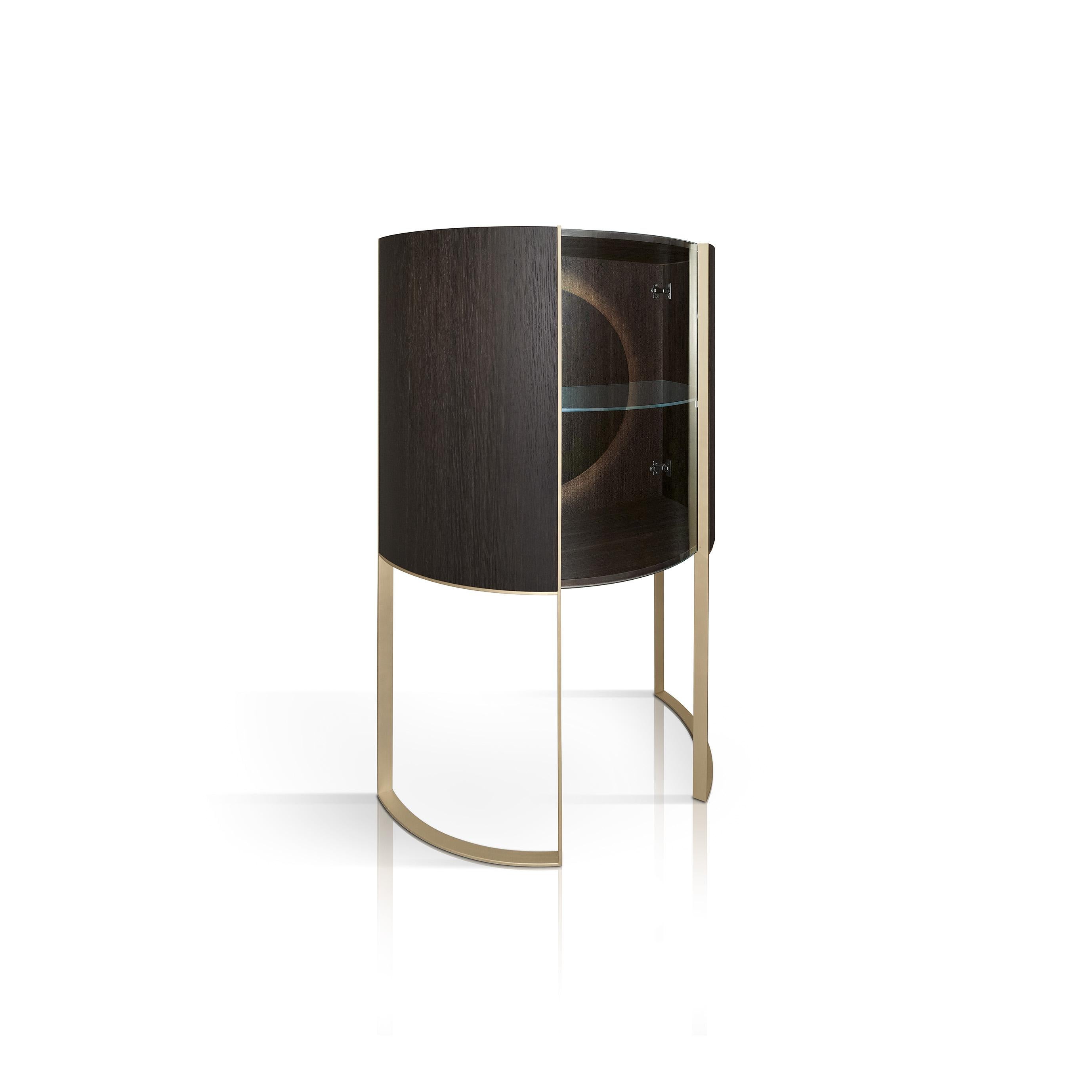 Modern functionality and harmonious aesthetics merge in this stunning display cabinet that brings to life the Classic concept of the showcase in a unique, modern design. The open base, with two brass U-shaped legs that follow the round profile of