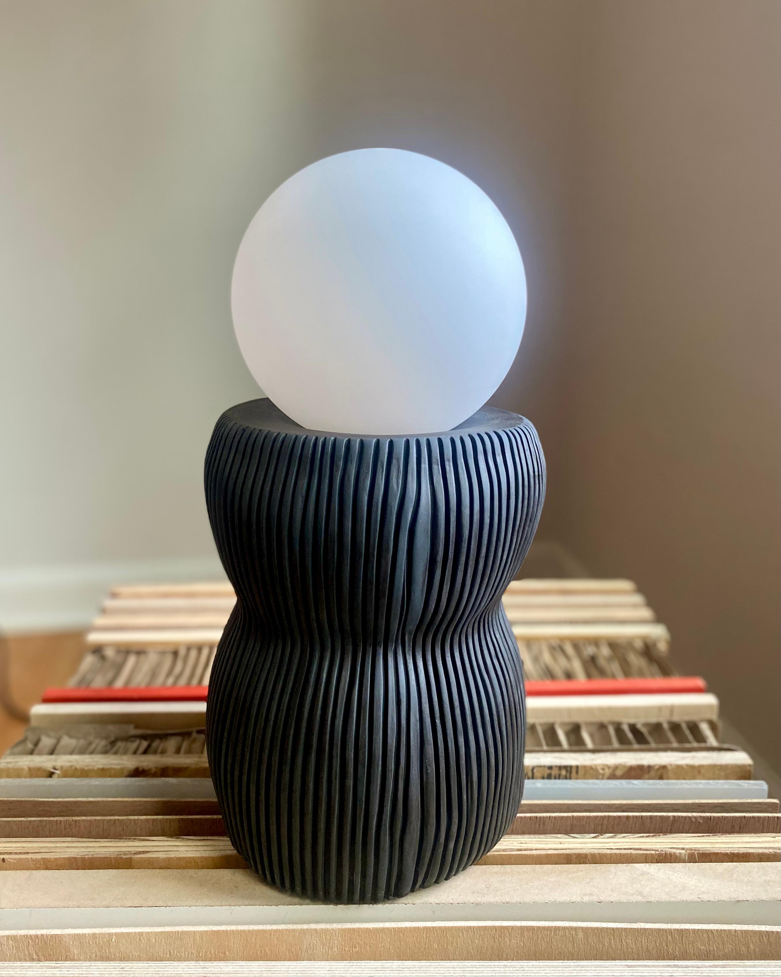This sculptural table lamp is hand made from house-made, black porcelain. Each lamp is sculpted and carved using multiple techniques to achieve a vitreous & smooth finish. The lamp is left unglazed to highlight the beauty of the materials.
If you