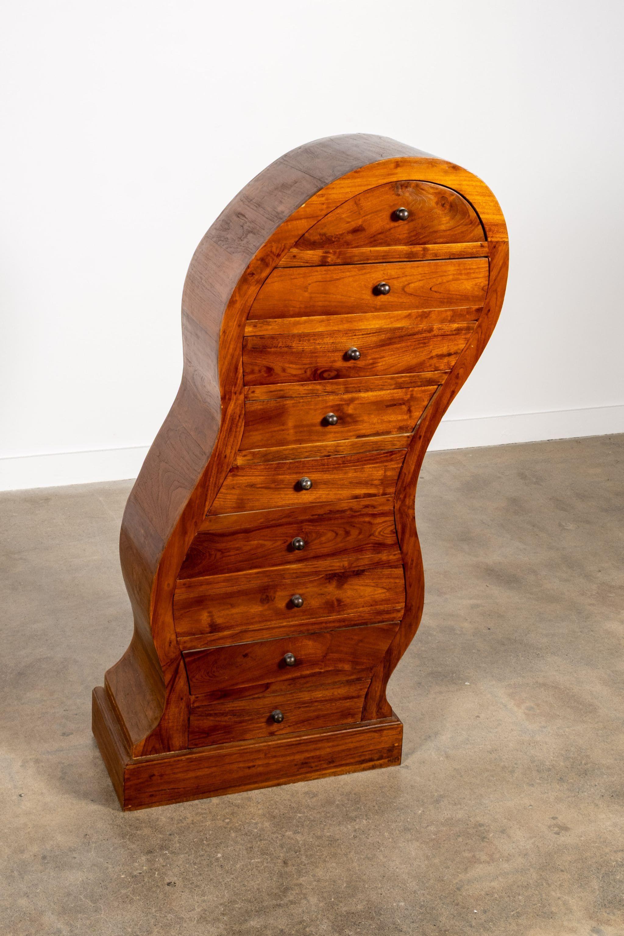 A sculptural take on classic storage. This tallboy twists tradition with its undulating silhouette and rich, honeyed wood grain. Each of the nine narrow drawers is a little offbeat, but perfectly functional — made for storing treasures, tools, or
