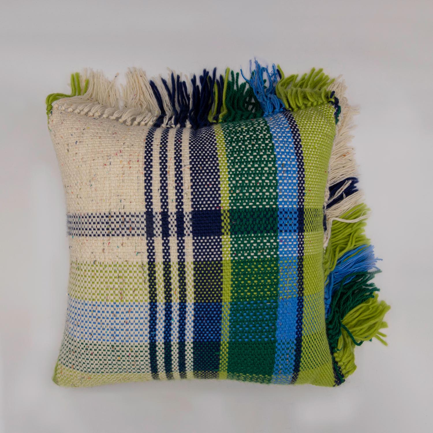 Tissé à la main en Toscane avec de la laine de Sardaigne, chaque coussin nécessite plus de deux jours de travail pour un artisan. Chaque face du coussin présente une variation du motif écossais caractéristique dans une alternance de couleurs.