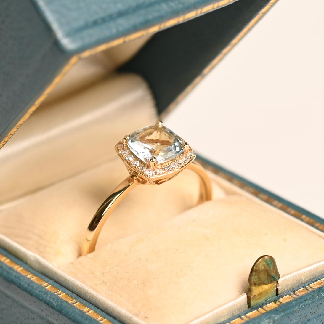 Este exquisito anillo de compromiso presenta una cautivadora aguamarina talla cojín de aproximadamente 0,90 quilates, cuyo sereno tono azul queda bellamente realzado por un delicado engaste con garras. El suave y etéreo resplandor de la aguamarina