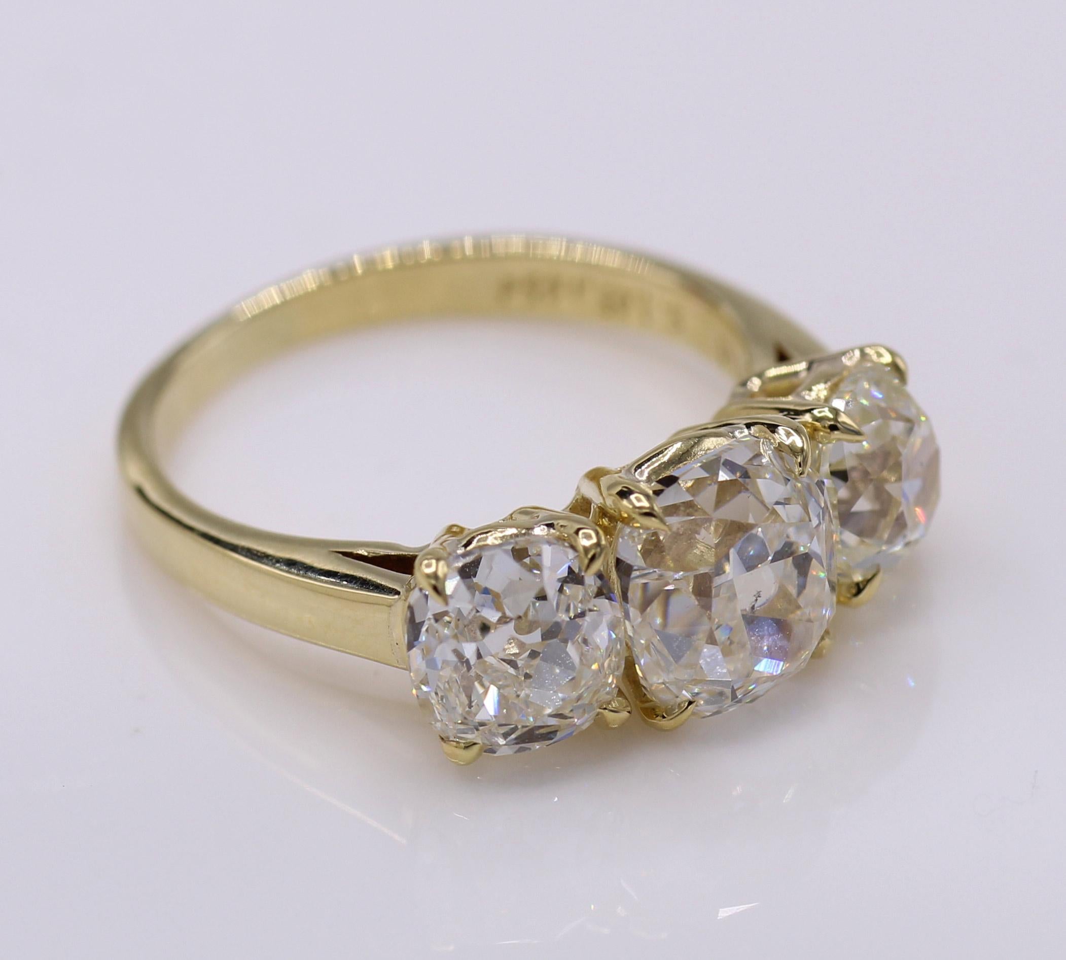 Three beautiful antique cut diamonds have been set in this magnificently hand-crafted 18 karat yellow gold mounting. All 3 diamonds are accompanied by reports from the GIA. The center cushion brilliant weighing 2.03 has a color grade of H with a