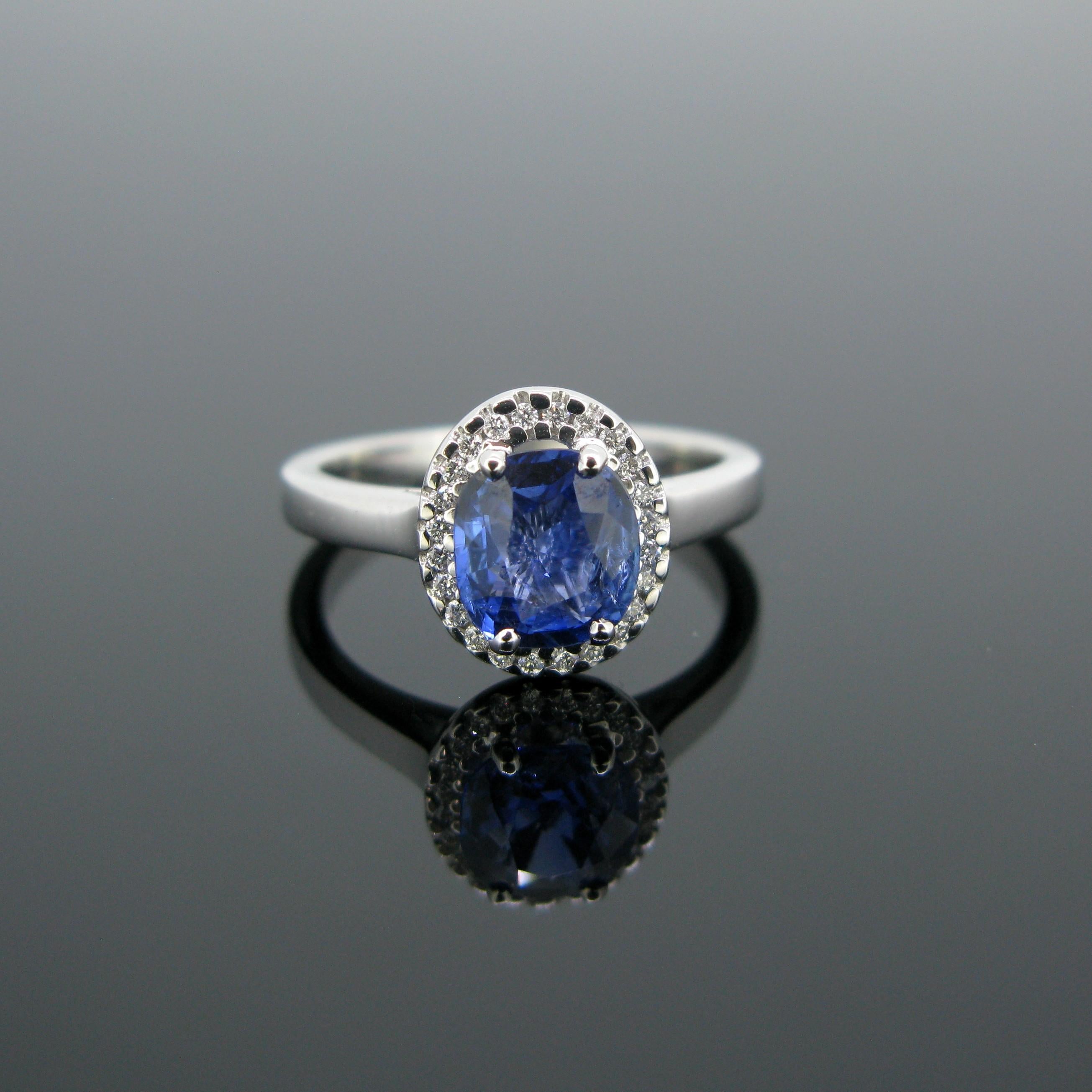This modern ring is made in 18k white gold and features a cushion cut Ceylon sapphire with a weight of 1.44ct and no indication of heating. It is surrounded by 24 small diamonds with an approximate total carat weight of 0.20ct. It is a beautiful