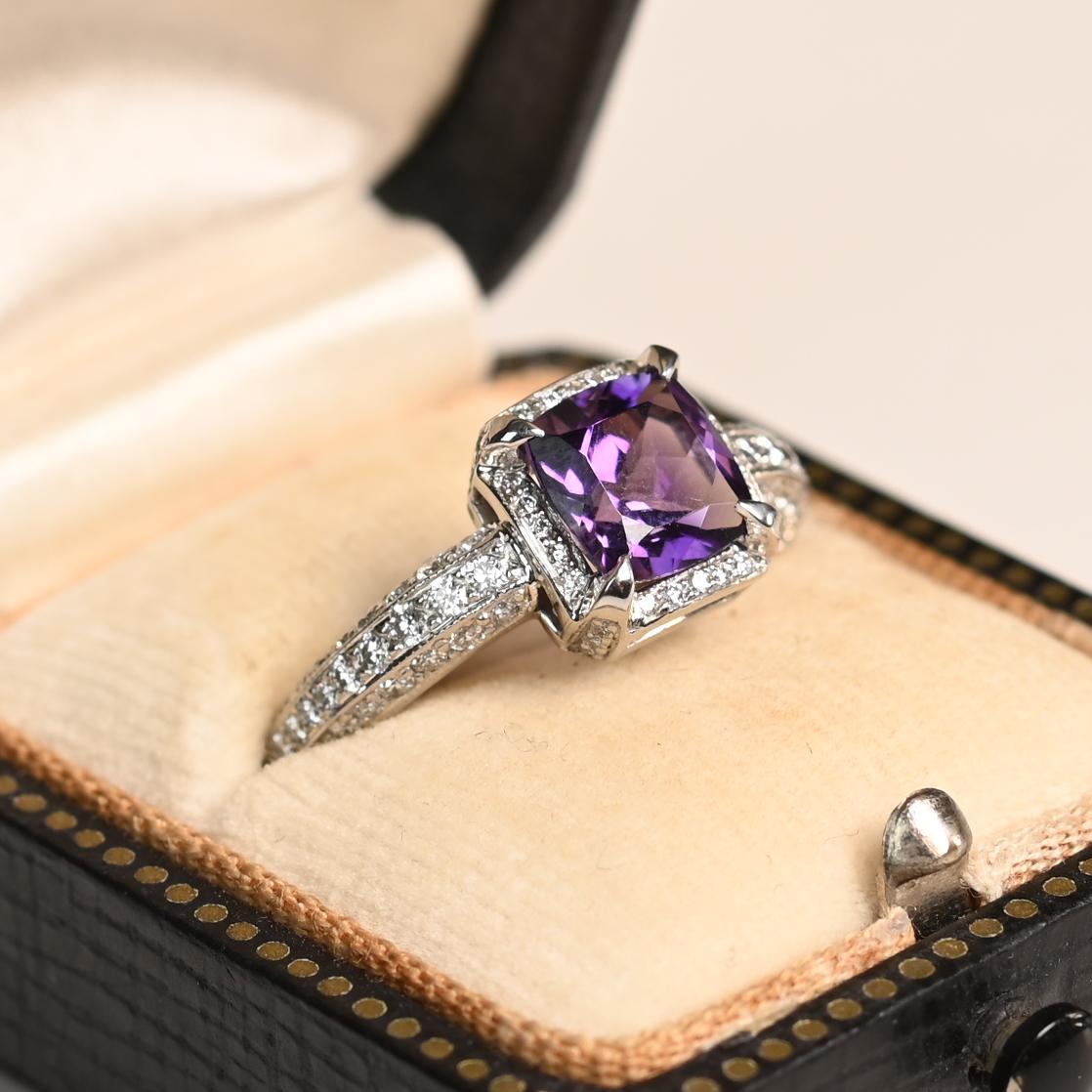 Questo squisito anello con pietre preziose presenta un'affascinante ametista di circa 1,30 carati con taglio a cuscino, la cui ricca tonalità viola irradia raffinatezza e fascino. L'ametista è saldamente incastonata al centro, permettendo alla luce