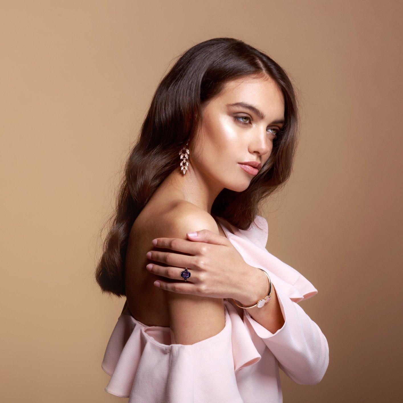 Este exquisito anillo exhibe una amatista alargada de talla cojín en su centro, que irradia un tono rico y regio. Flanqueando la gema central hay dos amatistas complementarias, que realzan la profundidad y el brillo de la pieza. La disposición de