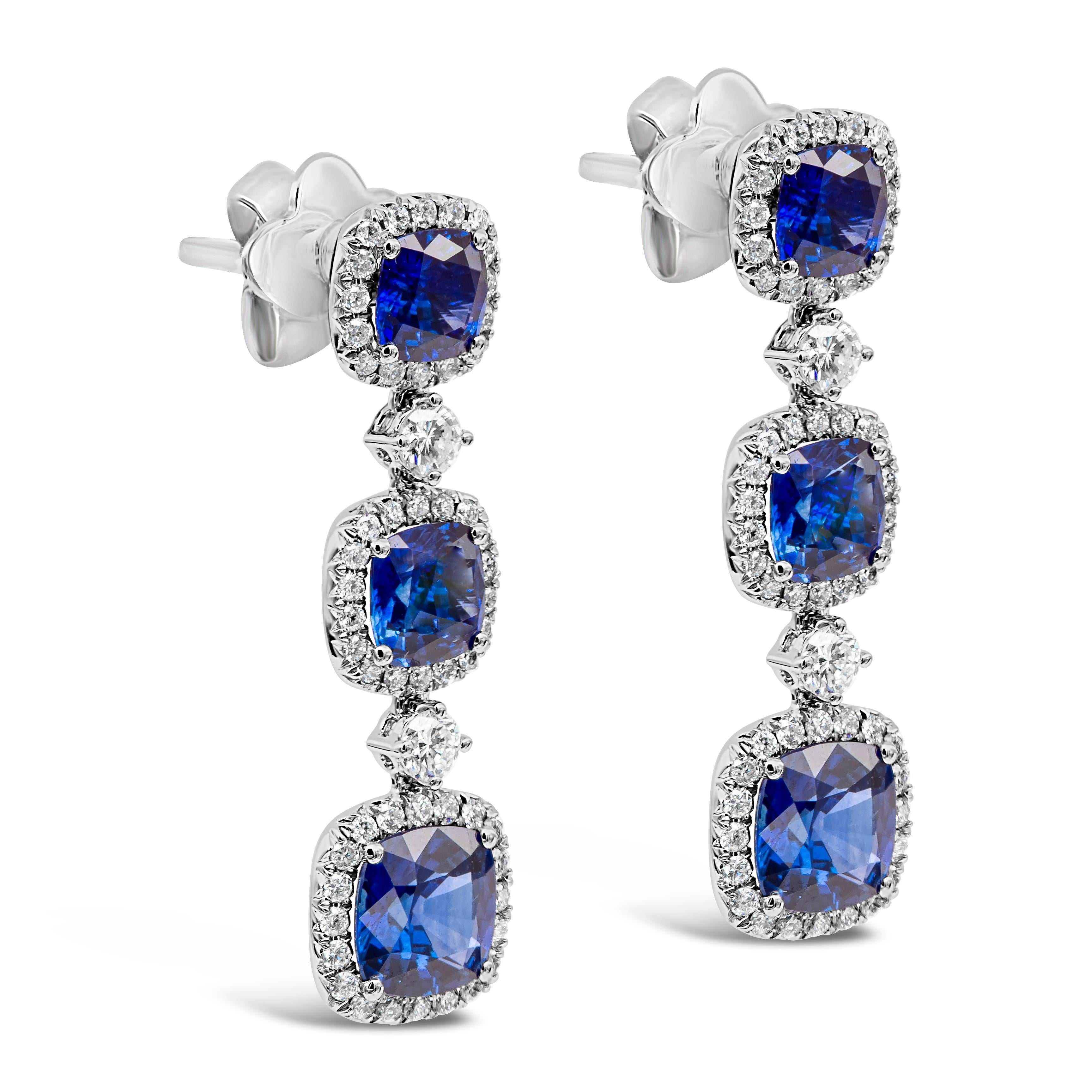 This extravagant dangle drop earrings features a row of cushion cut blue sapphires weighing 4.51 carats total, each set in a brilliant diamond halo. Diamonds weigh 0.73 carats total. Made in 18k white gold.

Style available in different price