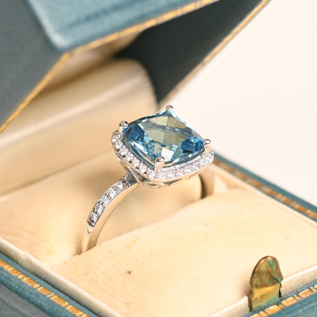 Cette exquise bague en or blanc 18 carats met en valeur une superbe topaze bleue taillée en coussin d'environ 2,60 carats, solidement maintenue par d'élégantes griffes. La teinte captivante de la pierre précieuse rayonne de brillance, ce qui en fait