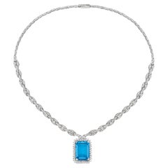 Collier de topaze bleue de taille octogonale relié à des diamants pavés en or blanc 18 carats