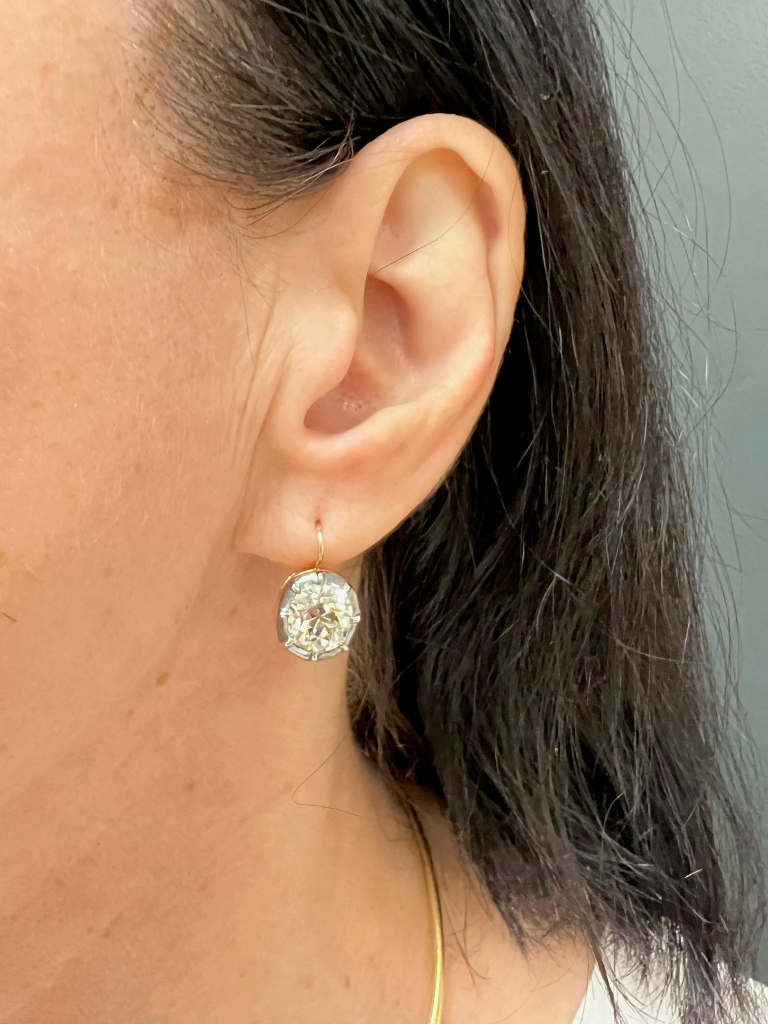 	A pair of Victorian silver and 14k gold earrings, featuring antique cushion cut diamonds. 
These dazzling gems are bezel set in silver, enforced with eight prongs. The yellow gold lever-back closure contributes to the earrings’ antique look, yet it