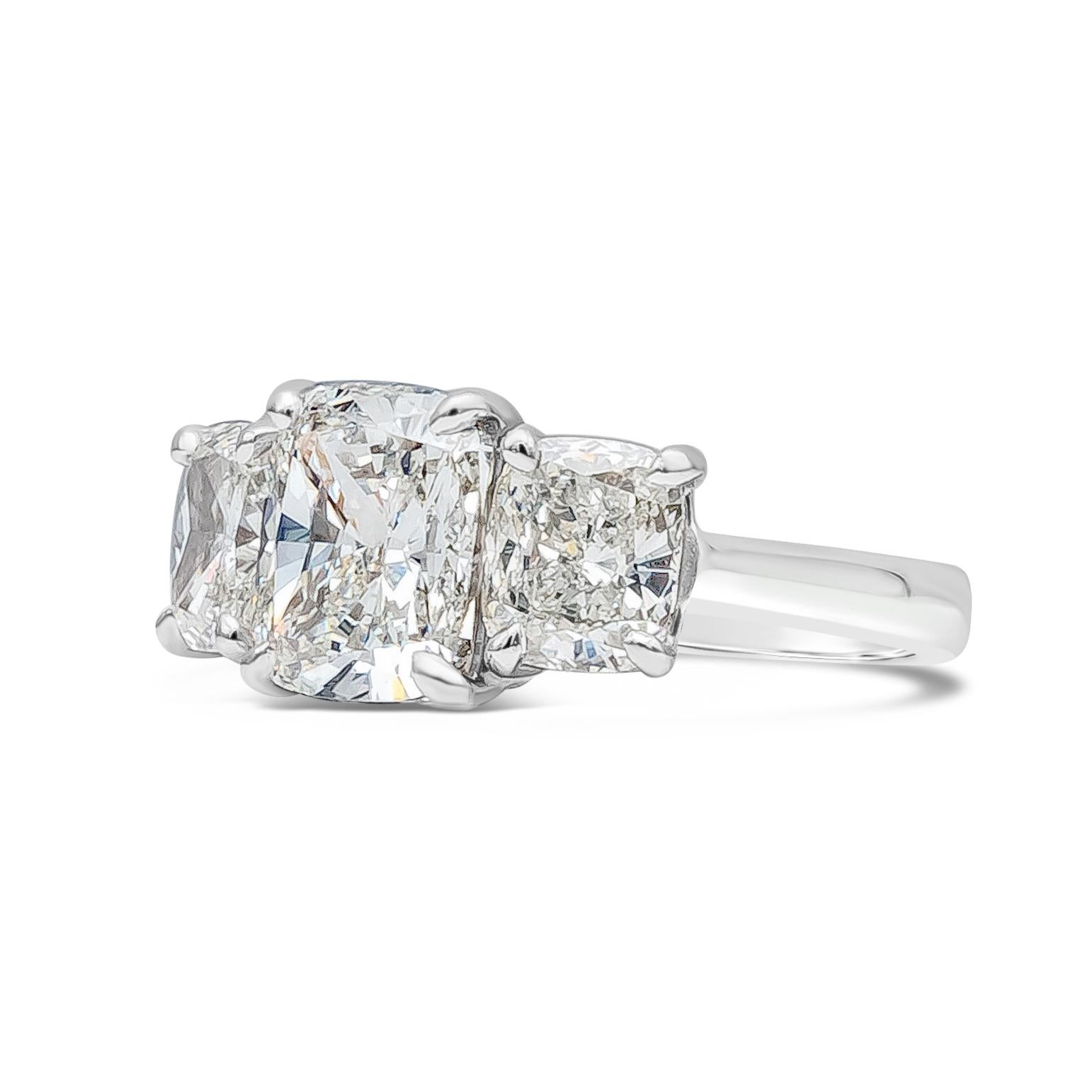 A stunning three stone engagement ring showcasing a GIA Certified Cushion Cut center stone weighing 5.02 carats total, H Color and VS1 in Clarity. Accompanied by GIA Certified cushion cut diamond on each side weighing 3.45 carats total, H Color and