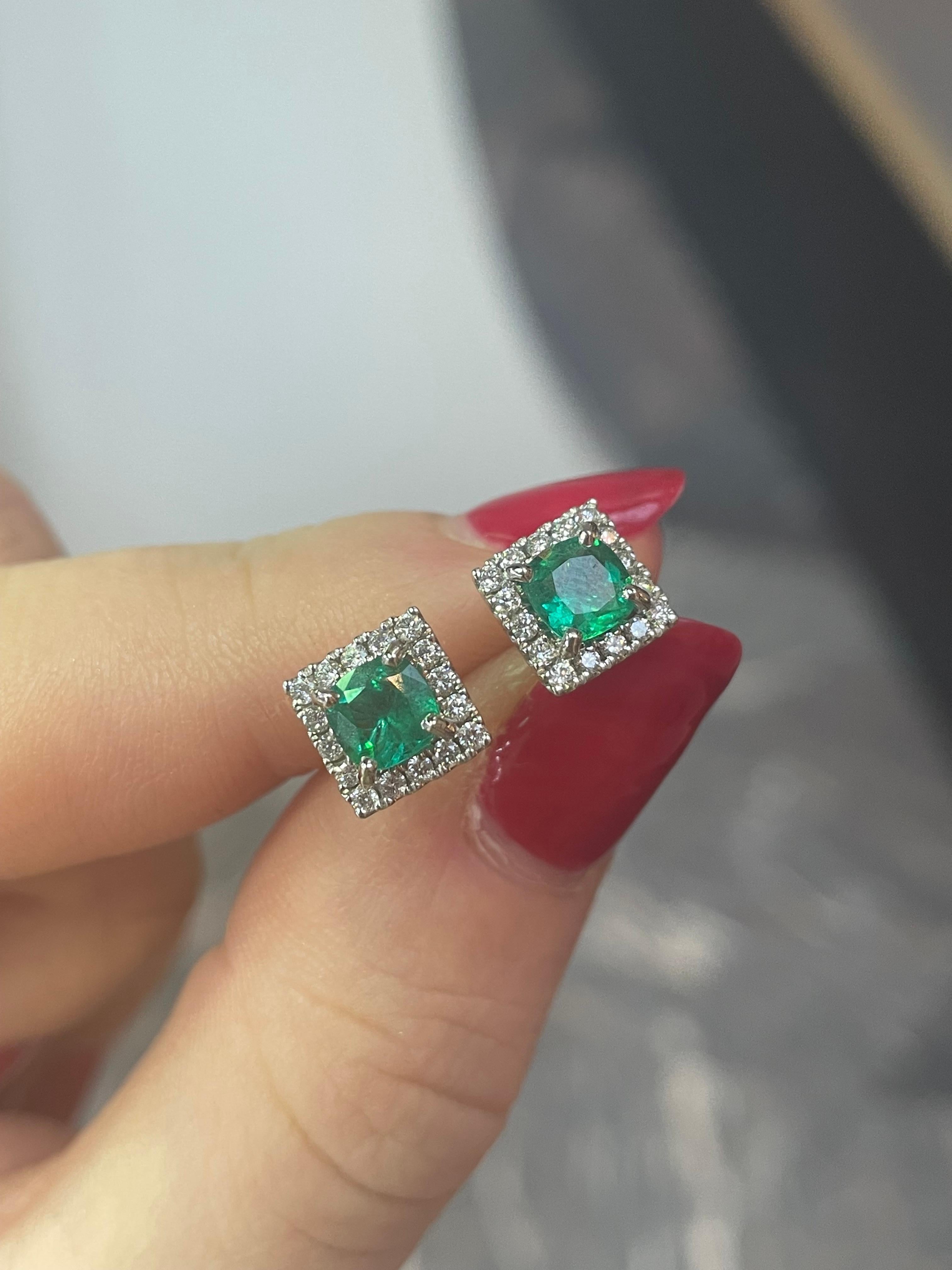 A pair of cushion cut emerald and diamond cluster earrings in 18 karat white gold.

Each earring is set to its centre with a beautiful cushion cut emerald of a vibrant colour. The emerald is set within a sparkling diamond set cluster of round