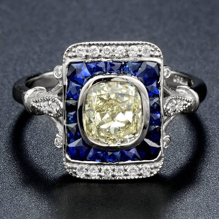 Center Cushion Cut Fancy Diamond 1.25 Carat surrounded by French Cut Blue Sapphire 18 pieces 1.05 Carat and small Diamond 20 pieces 0.13 Carat.

The ring was made in Platinum size US#7
