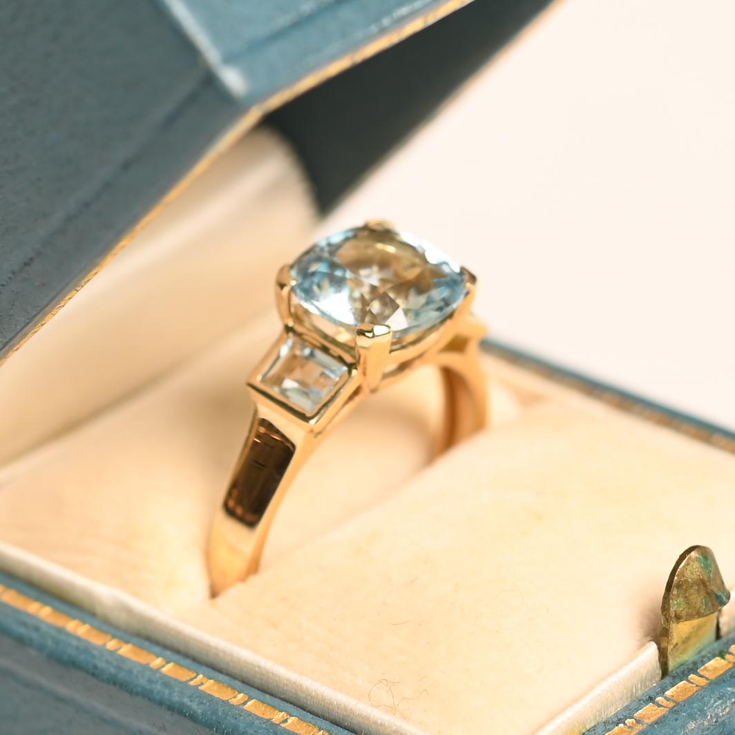 Cette bague exquise présente en son centre une superbe aigue-marine taillée en coussin, sertie pour en souligner l'éclat. La pierre précieuse captivante pèse environ 1,90 carat et présente une teinte bleue envoûtante qui capte magnifiquement la