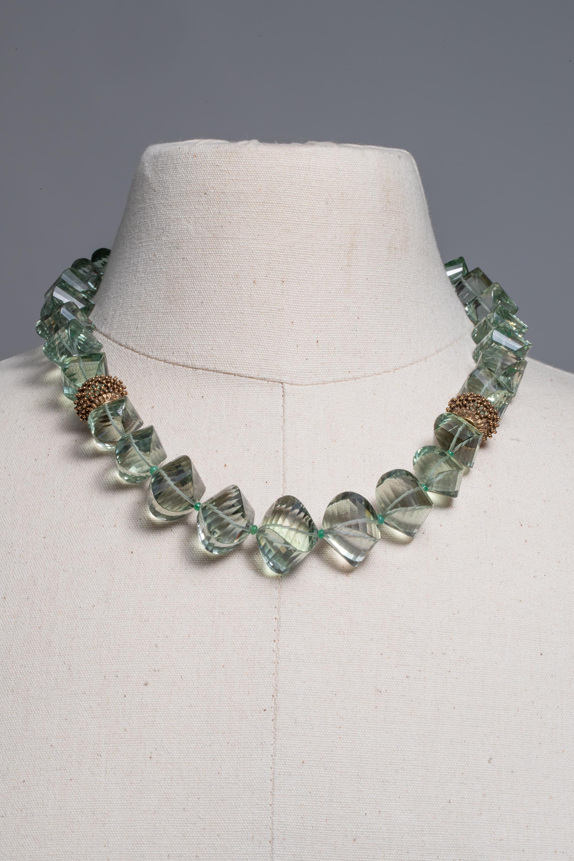 Améthyste verte (prasiolite) facettée et taillée en coussin, magnifiquement ondulée, avec des perles texturées en or 18K au niveau de la clavicule.  Collier de perles légèrement graduées avec des émeraudes entre les deux, avec un fermoir en or 18K