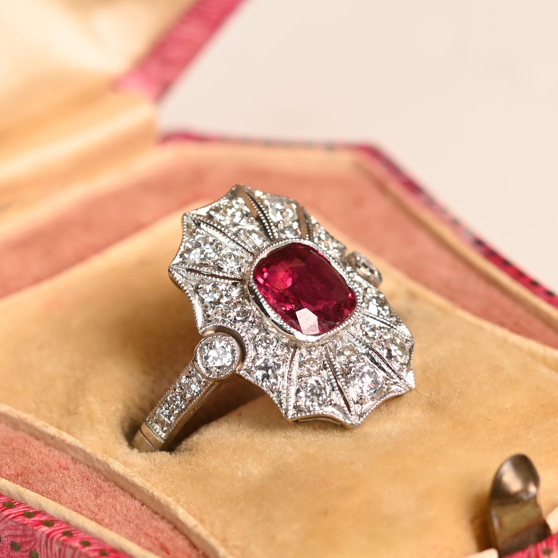 Cette exquise bague en platine met en valeur un captivant rubis naturel de Birmanie d'environ 0,9 carat, taillé en coussin et solidement serti au centre de la bague. Entourant le rubis vibrant, une délicate rangée de diamants sertis en pavé rehausse