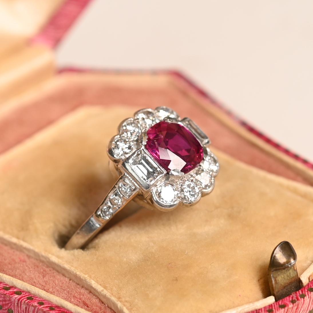 Dieser exquisite Platinring im Vintage-Stil besticht durch einen natürlichen Rubin im Kissenschliff mit einem Gewicht von etwa 1,3 Karat. Der satte, leuchtende Farbton des Rubins wird durch elegant gefasste Diamanten im Baguetteschliff auf beiden