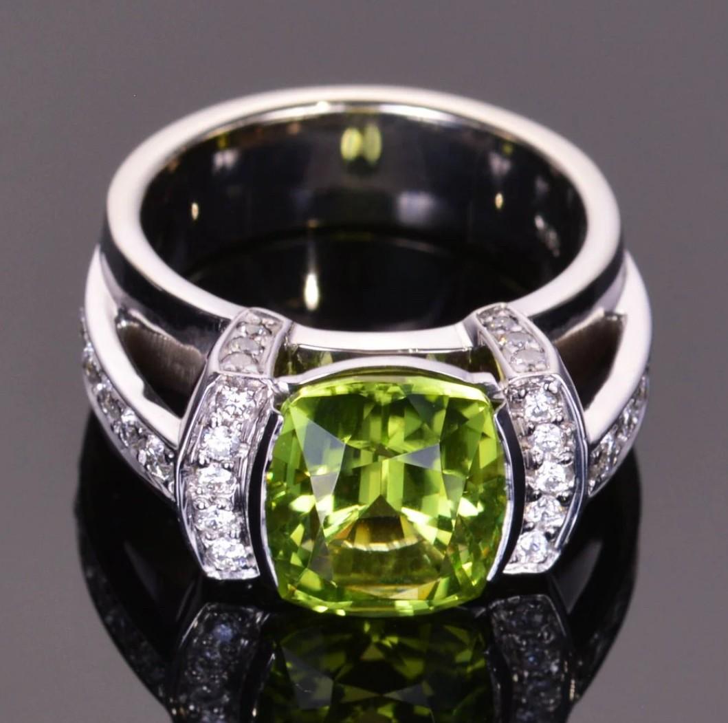 Dieser brillante Peridot im Kissenschliff hat 5,42 Karat und wird von schönen Diamanten in einem modernen Cocktailring aus 18 Karat Weißgold akzentuiert. Die Abmessungen dieses Rings sind 11 mm x 16 mm. Die Ringgröße ist 6,5.

Weitere Größen sind